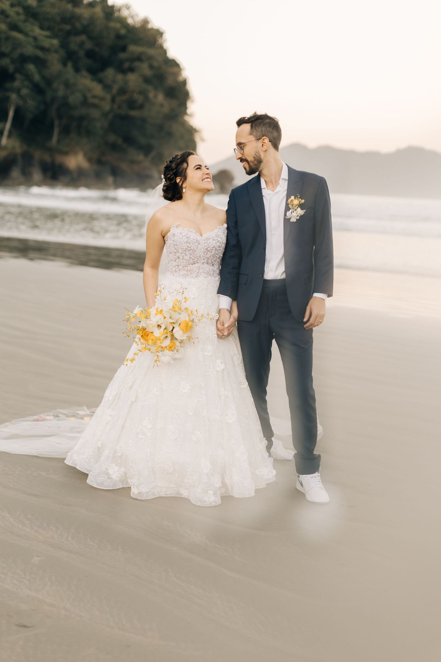 Dreamy beachside wedding photos with a couple walking along the shoreline at sunset.