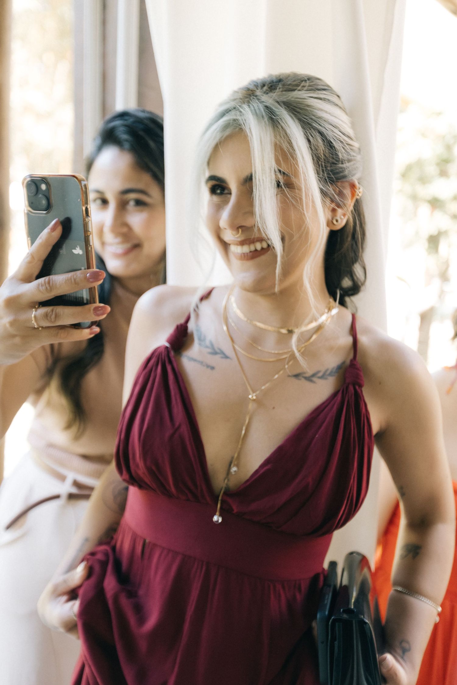 Bridesmaids in burgundy dresses gather together for getting ready photos.