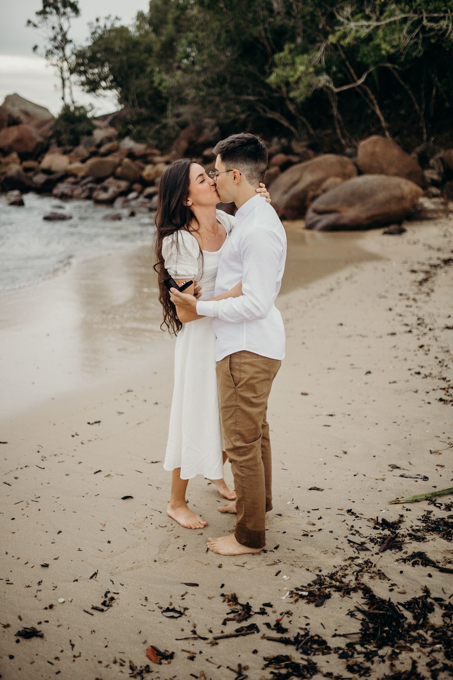Sweet embrace between couple on beach during surprise proposal.