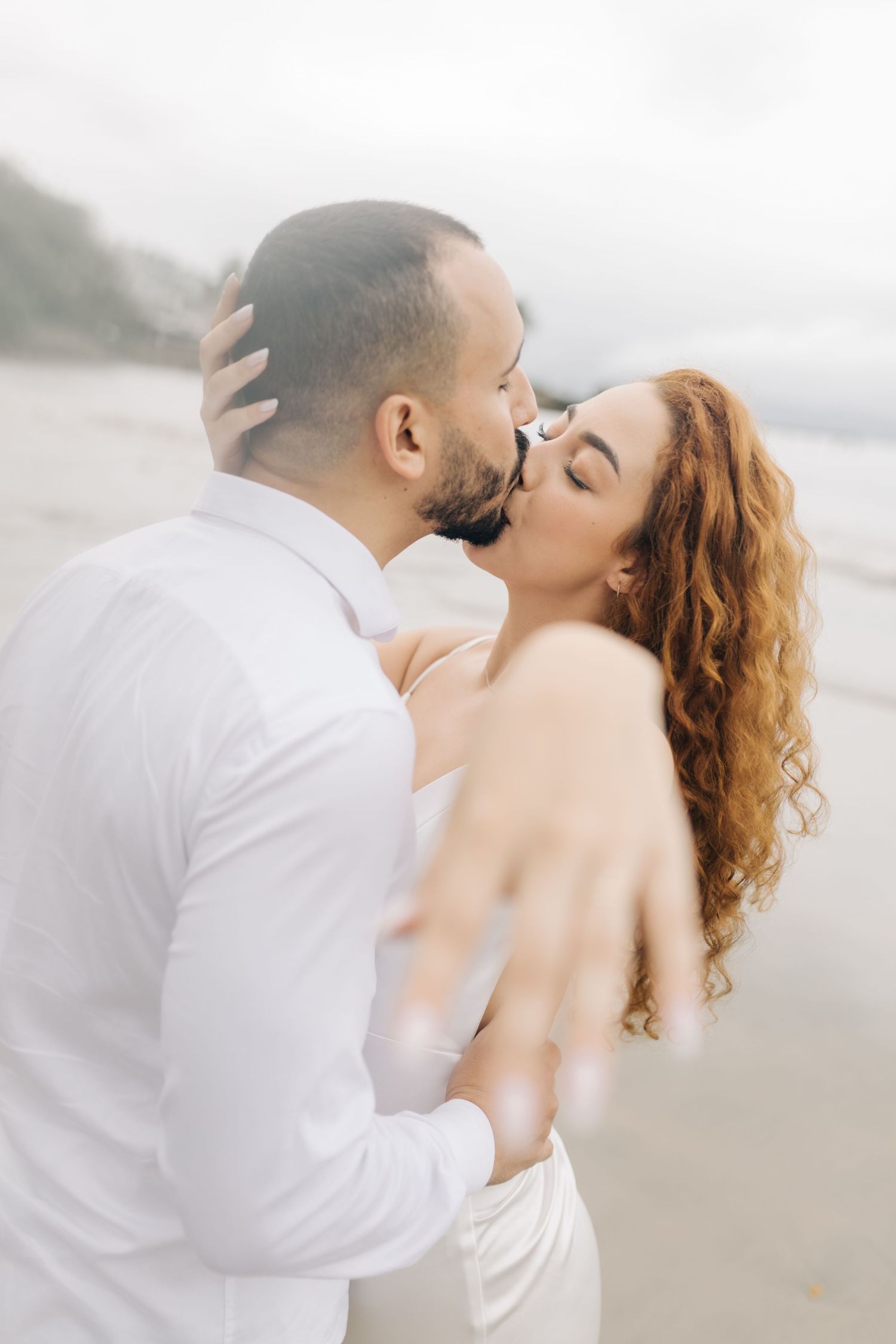 Intimate beachside portraits with soft lighting and romantic poses against cloudy sky.