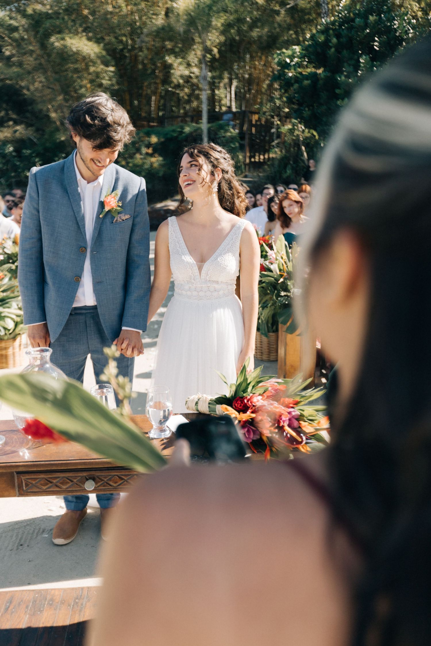 Newlyweds hold hands during their outdoor garden ceremony.