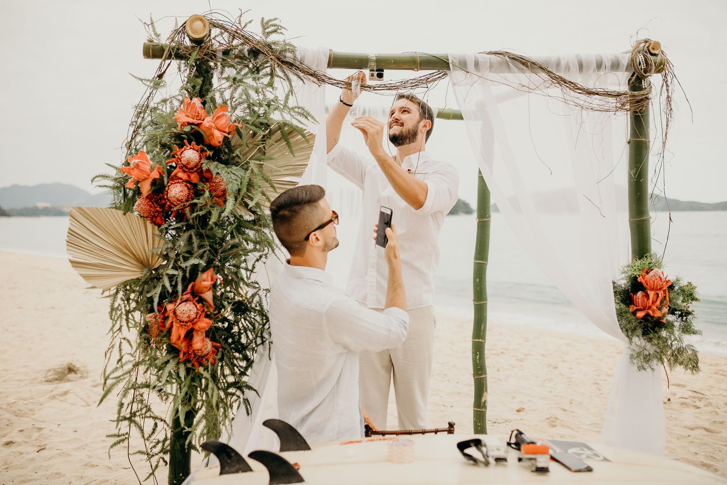 Outdoor beach wedding altar decorated with coral and white flowers against an ocean backdrop.
