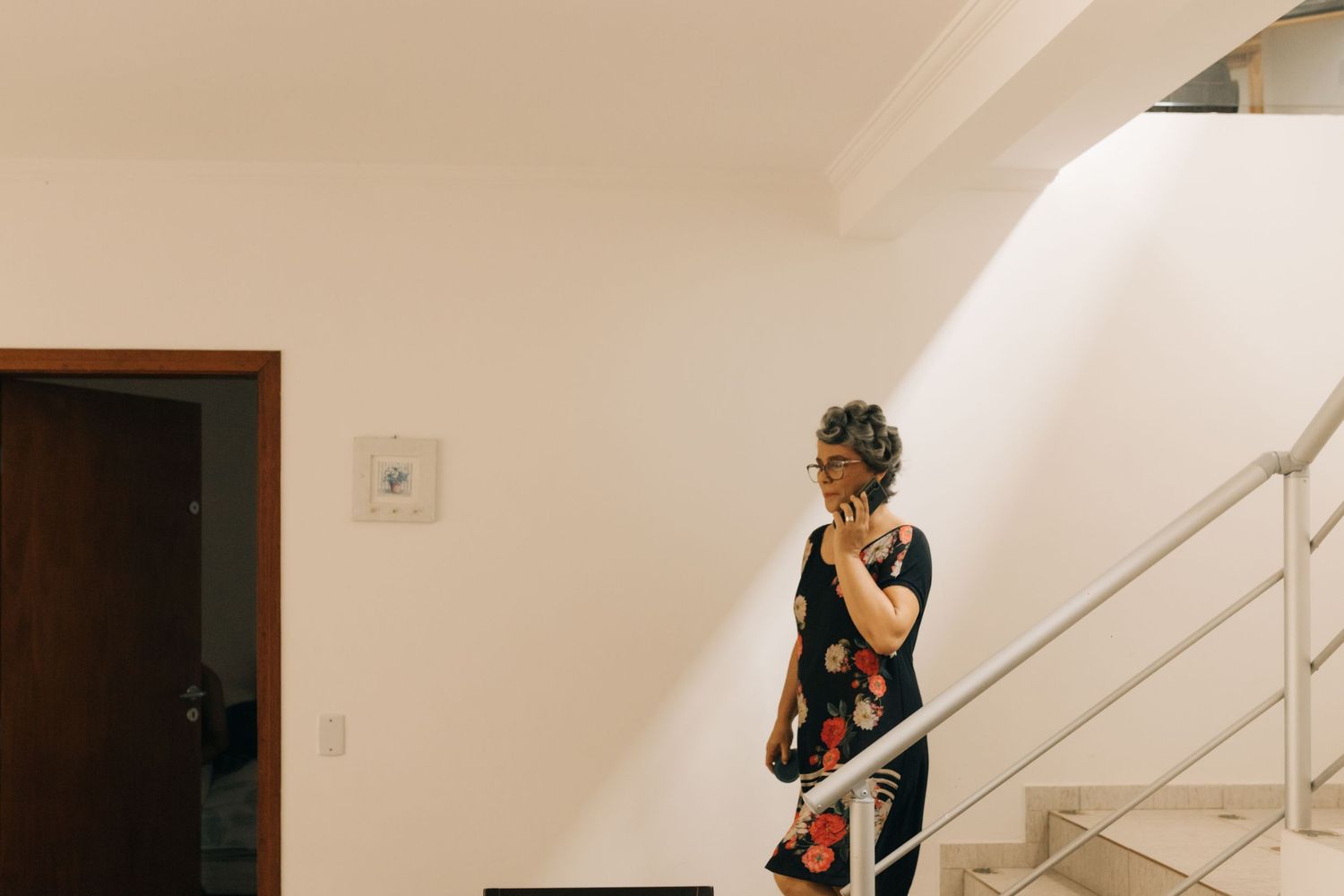 Person standing on modern white staircase looking at phone.
