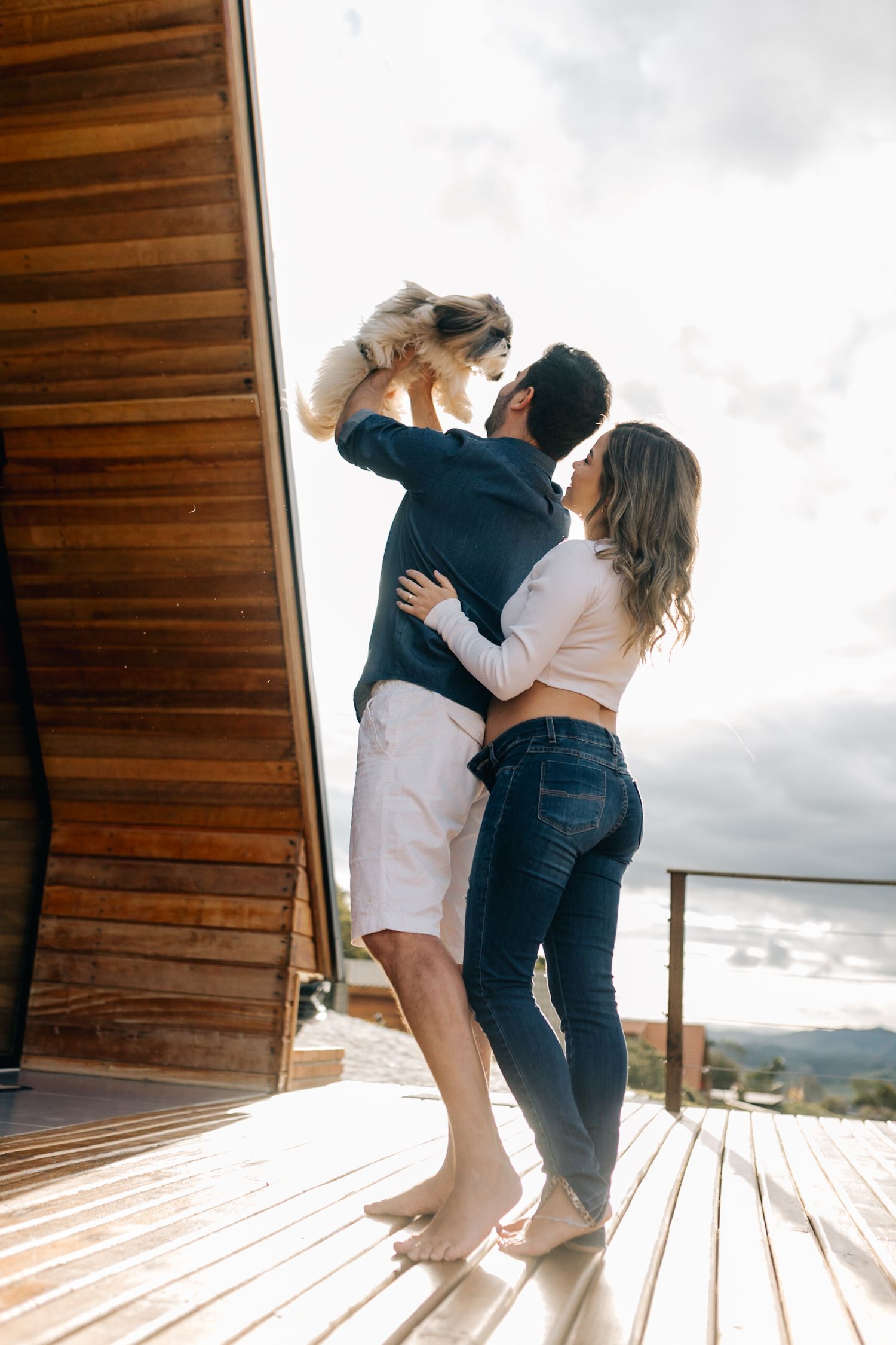 Playful couple dancing and embracing on a wooden deck with mountains in the background.