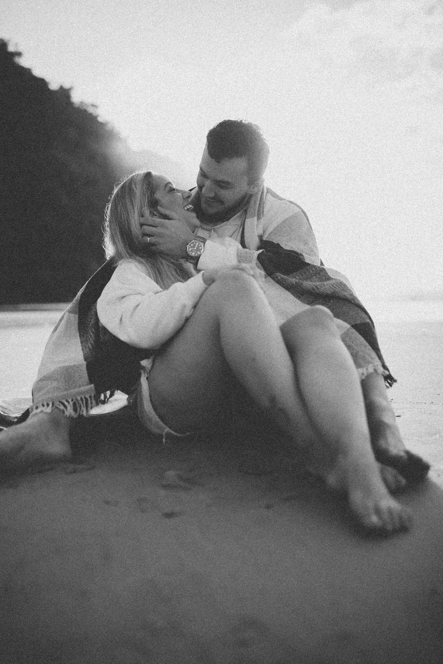 A romantic black and white photo of a couple embracing on the beach.