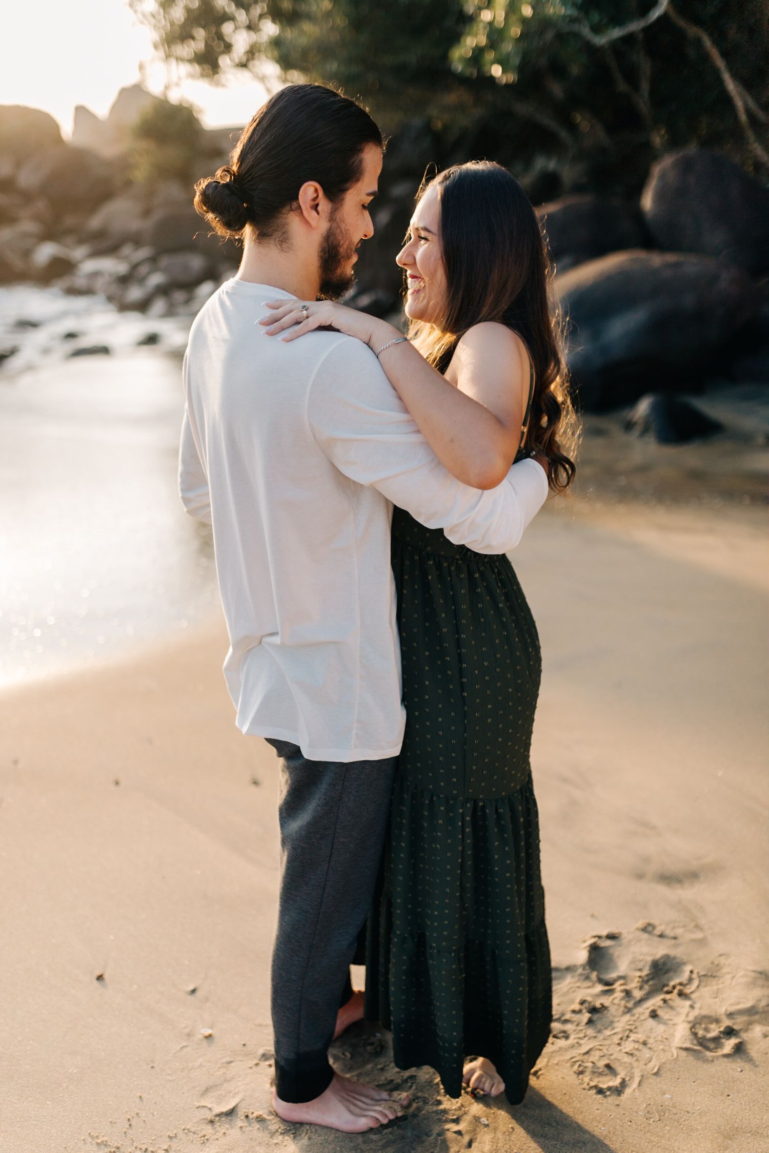 Tender moment shared between couple on sandy beach during golden hour.