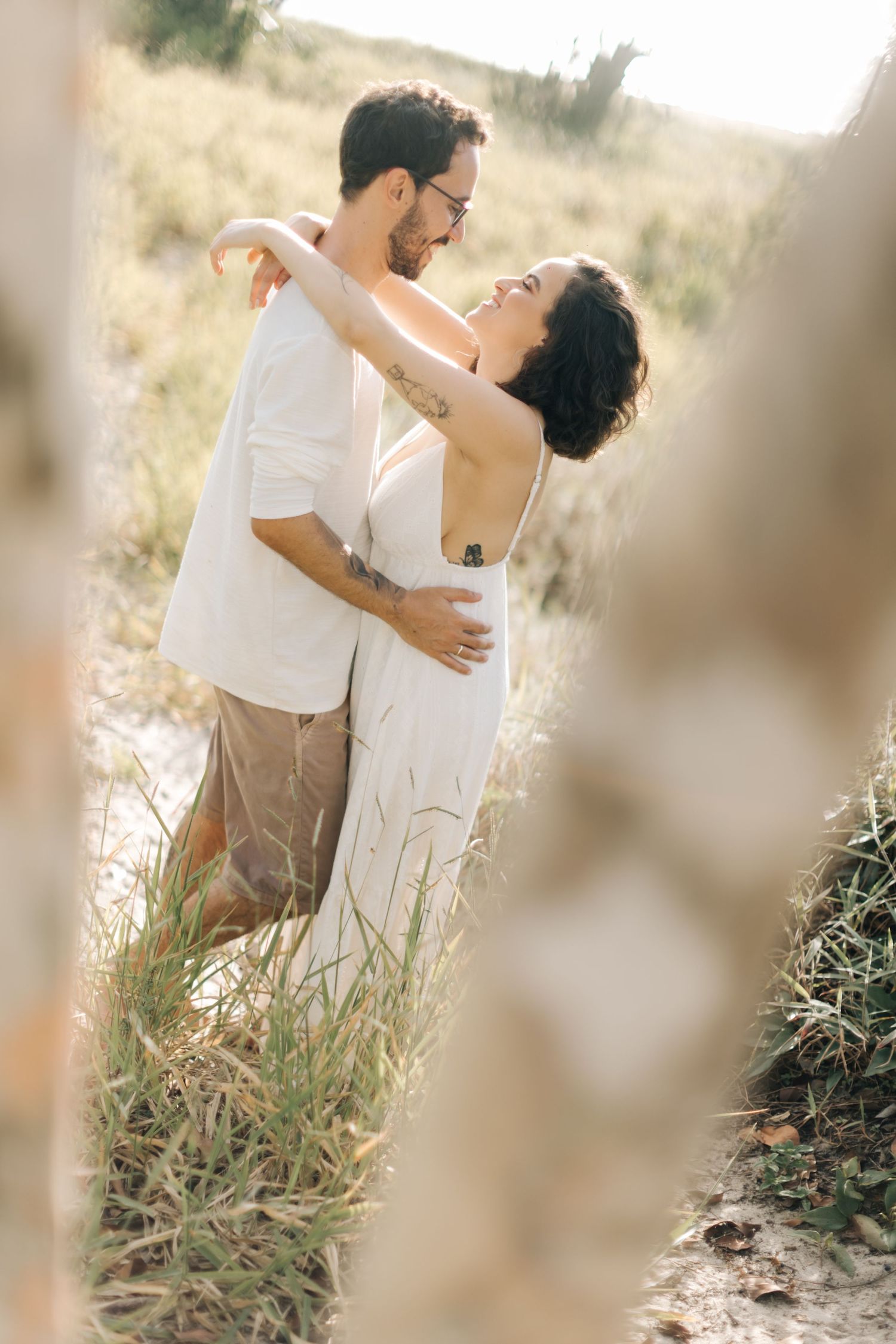 Dreamy couple portraits captured through grass in natural outdoor setting.