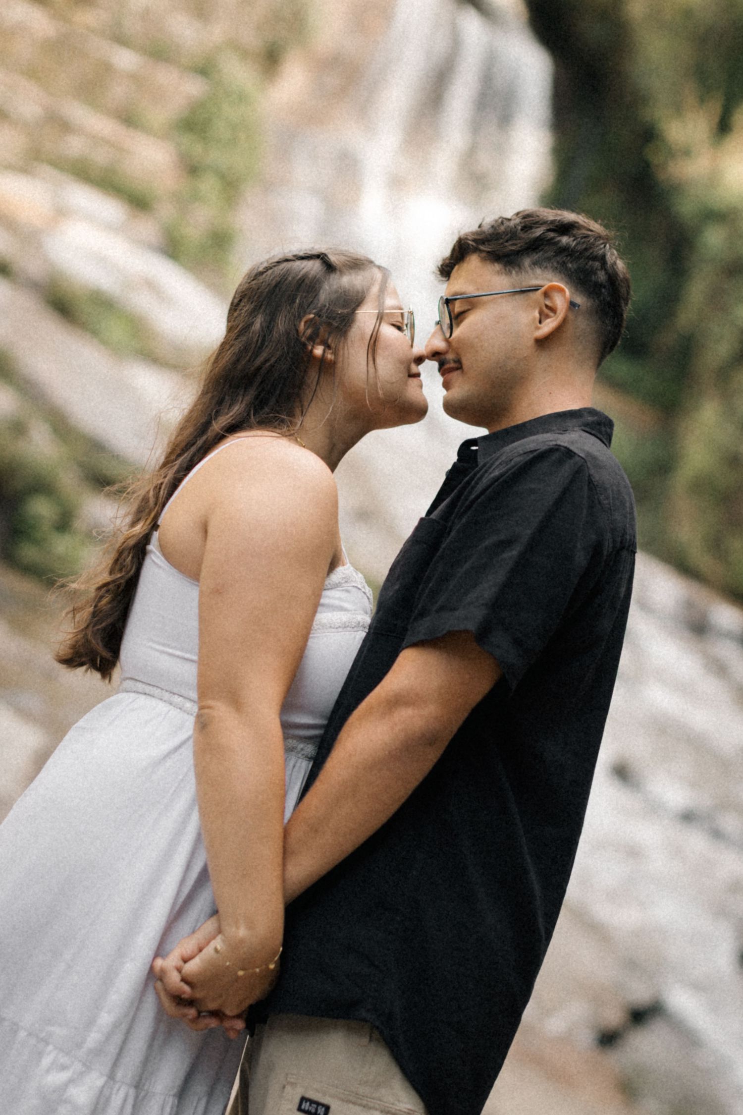 A couple shares an intimate moment near a waterfall, with multiple frames showing different angles.