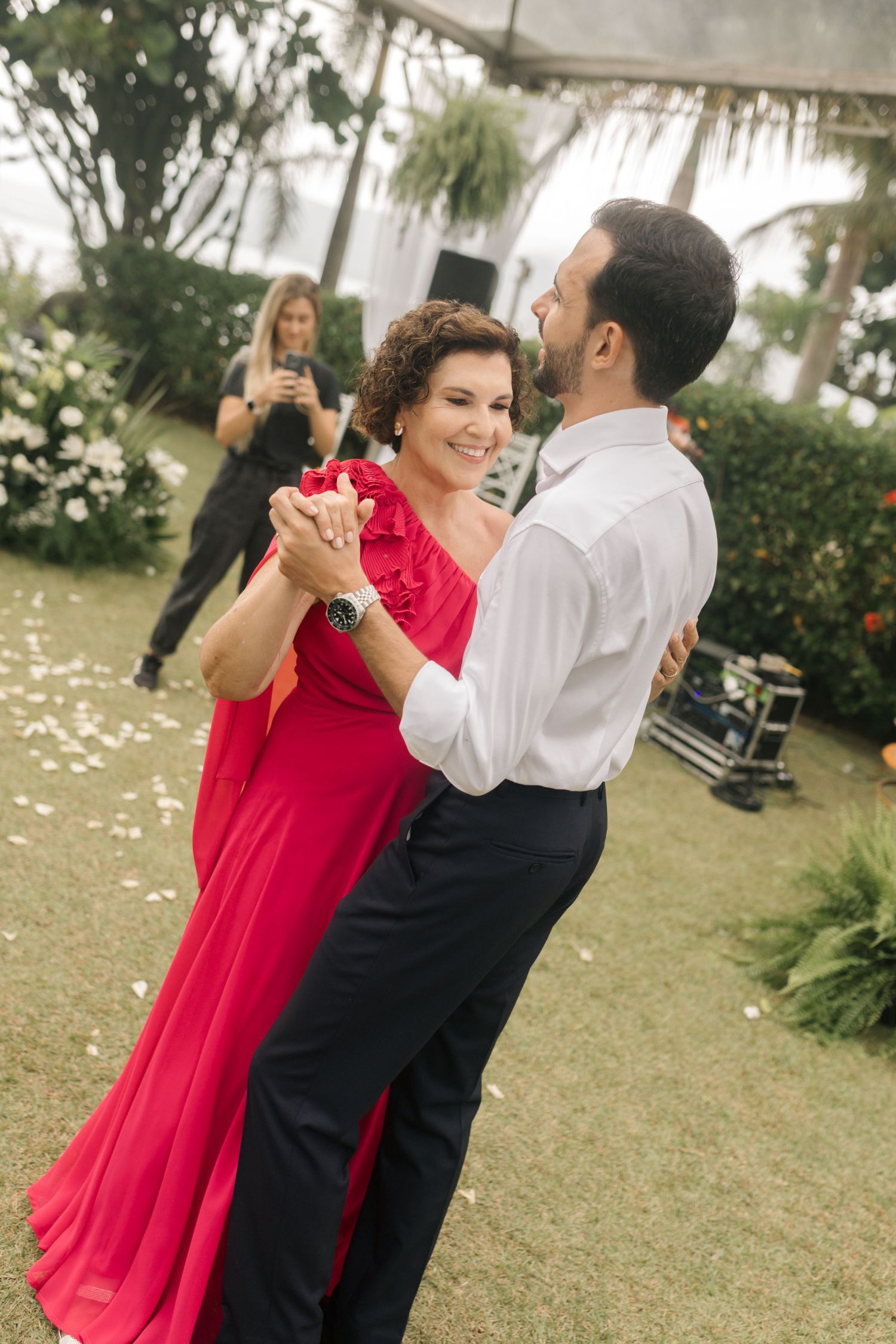 Couple in formal attire dancing together at an outdoor wedding reception under a tent.
