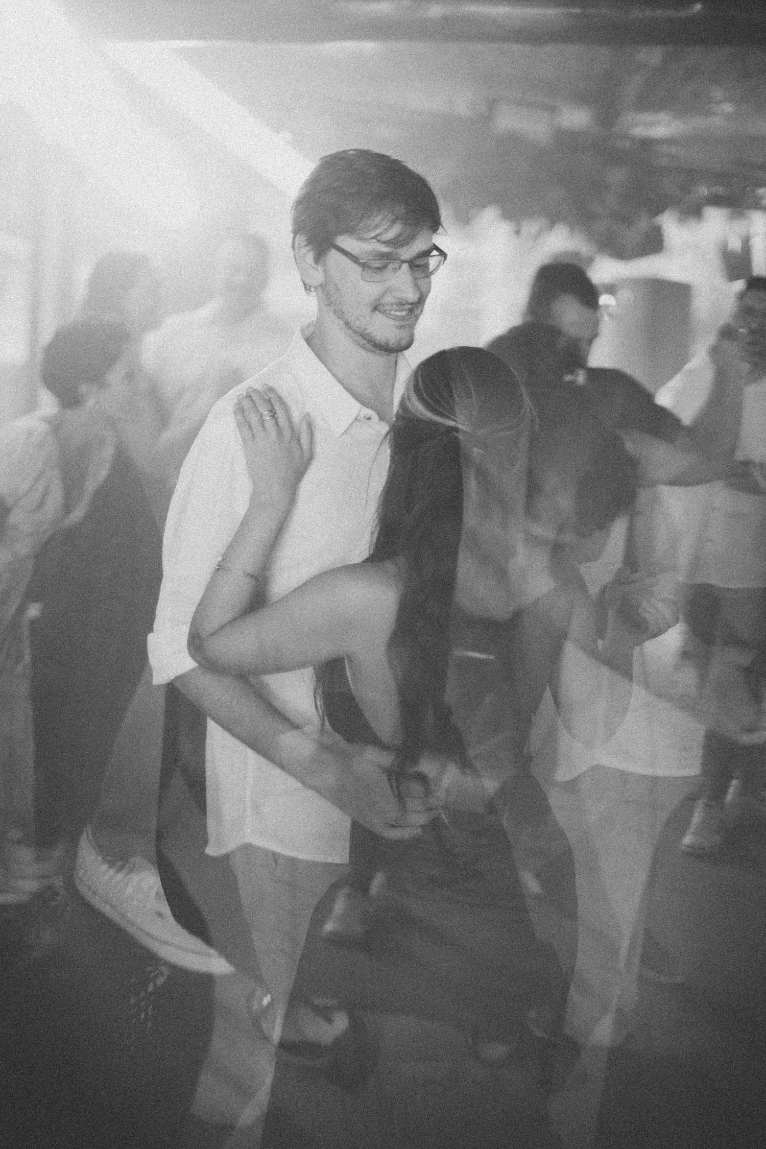 Vintage-style black and white photo captures blurred motion of wedding reception dancers.