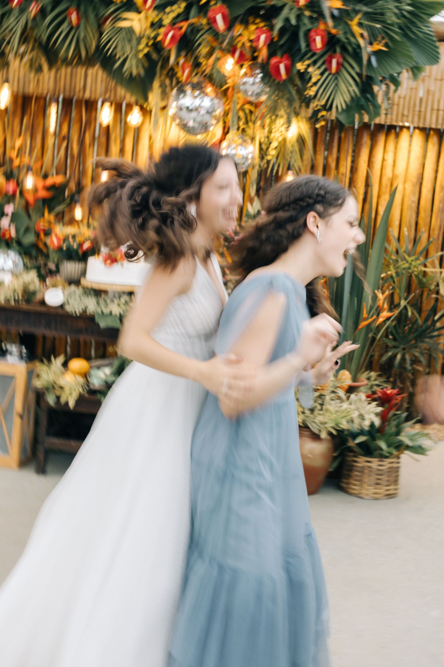 Blurred action shot of wedding celebration with tropical decorations and warm lighting.