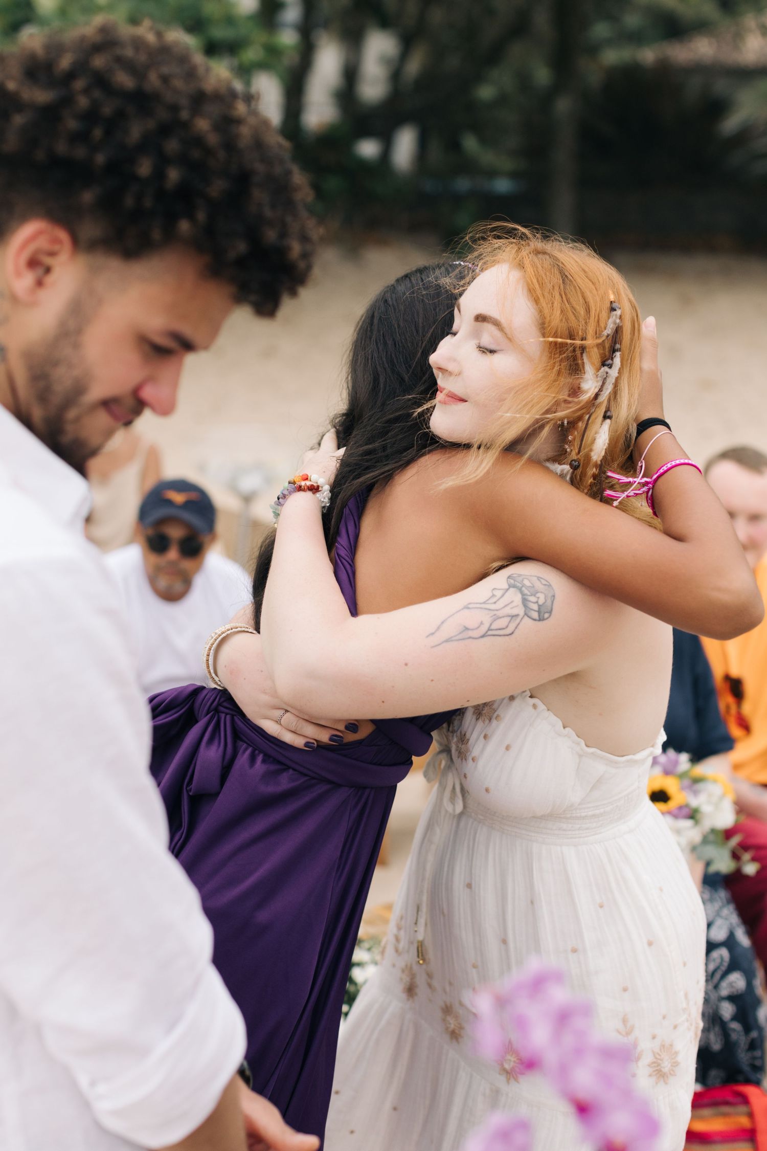 A candid moment between two people embracing during an outdoor beach celebration.