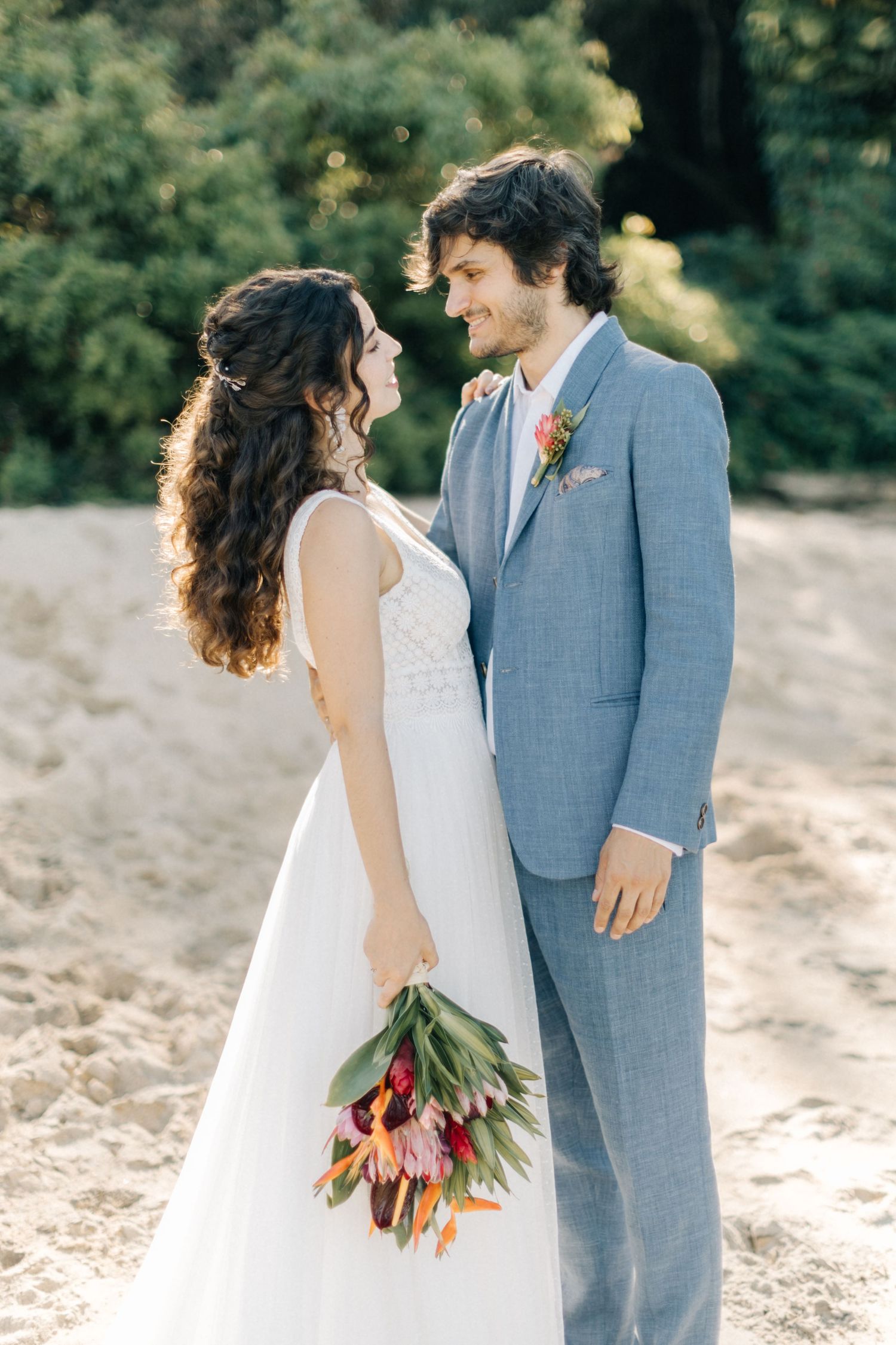 Couple shares romantic moment on beach with colorful tulip bouquet.