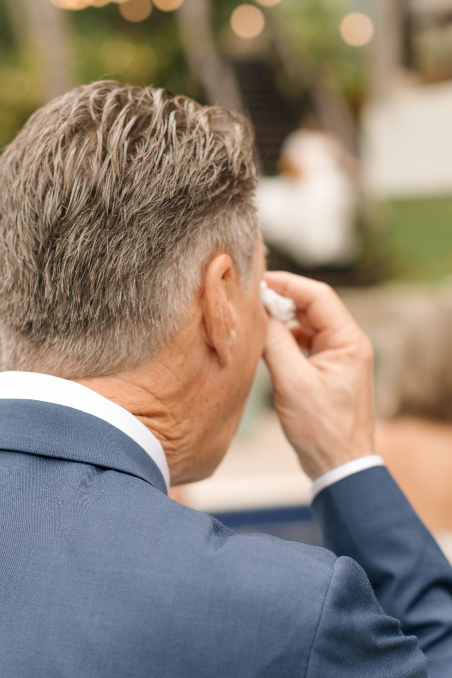 Close-up profile view of someone in a blue suit wiping their eye during an emotional moment.