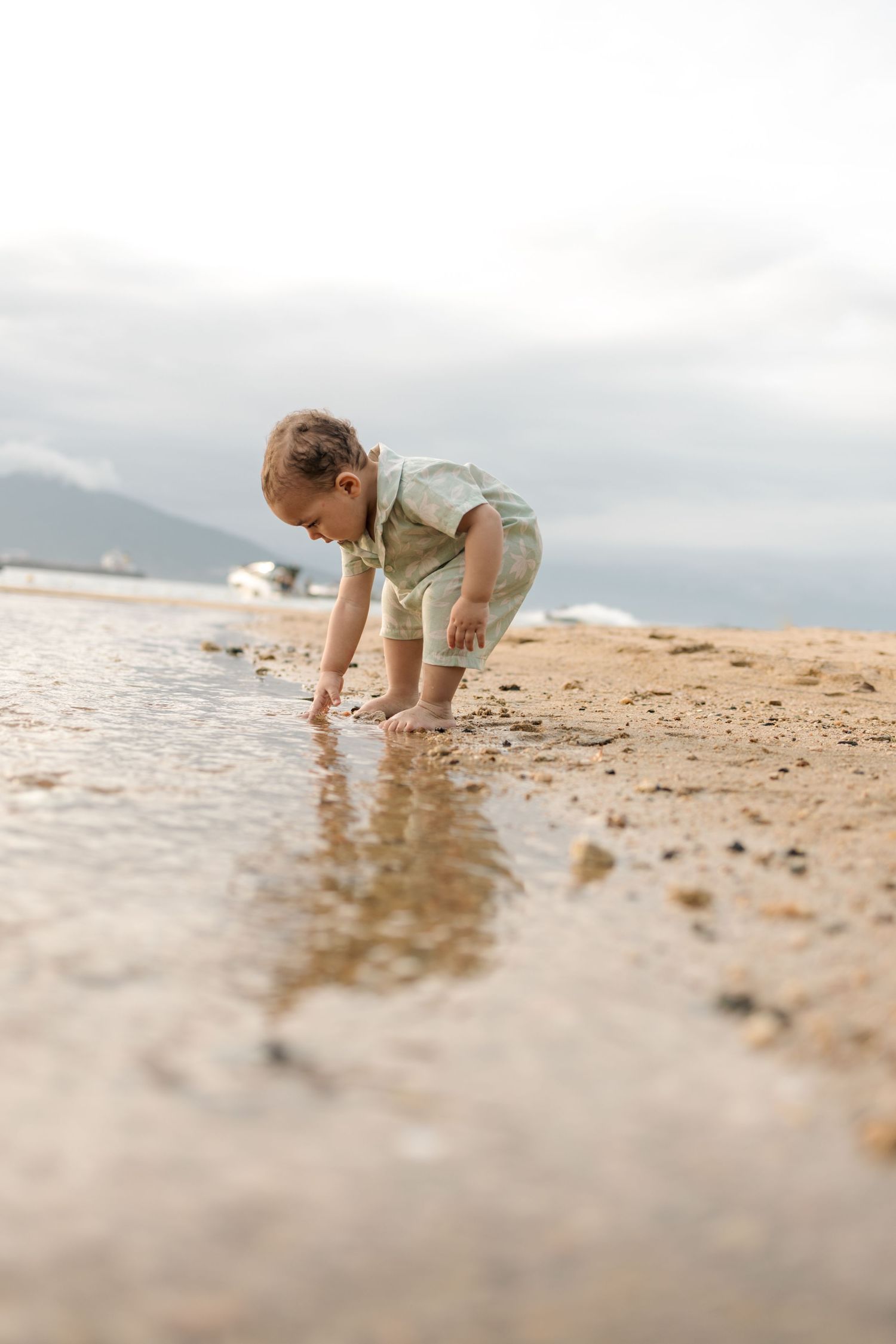 Child exploring and playing in the shallow water at the beach's edge.