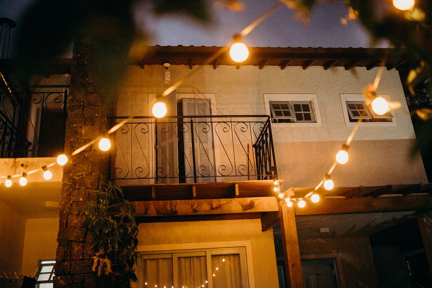 String lights illuminate a rustic outdoor patio venue with wooden beams and decor.