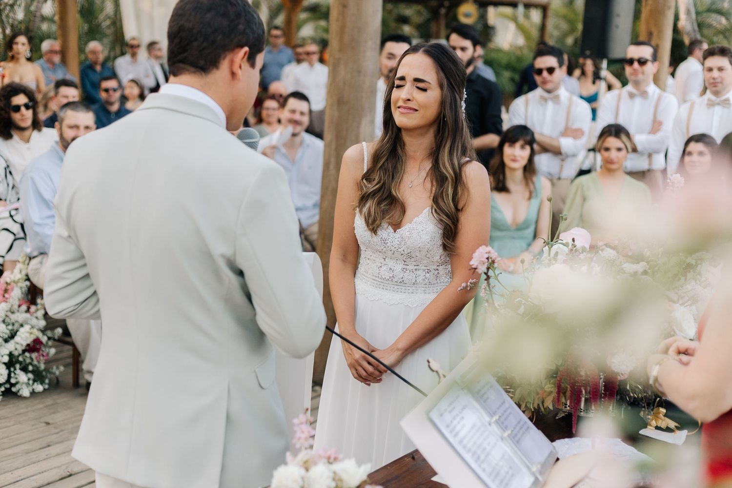 A couple exchanging vows during an outdoor wedding ceremony surrounded by guests on a beautiful day.