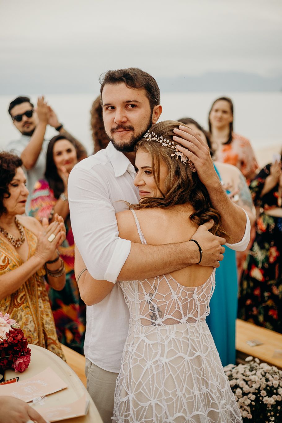 Couple dancing together during a sunset beach wedding celebration with guests in the background.