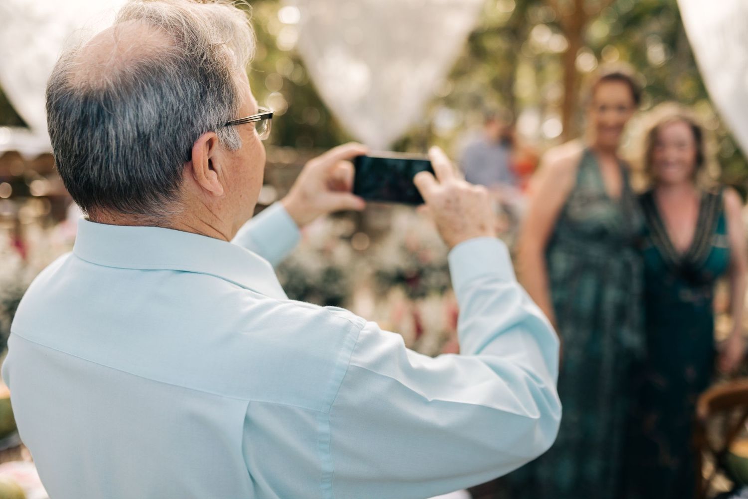 Guest taking photos at outdoor waterfront wedding ceremony.