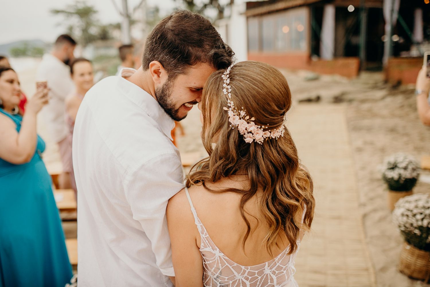 Intimate outdoor wedding ceremony with floral decorations and white fabric backdrop.