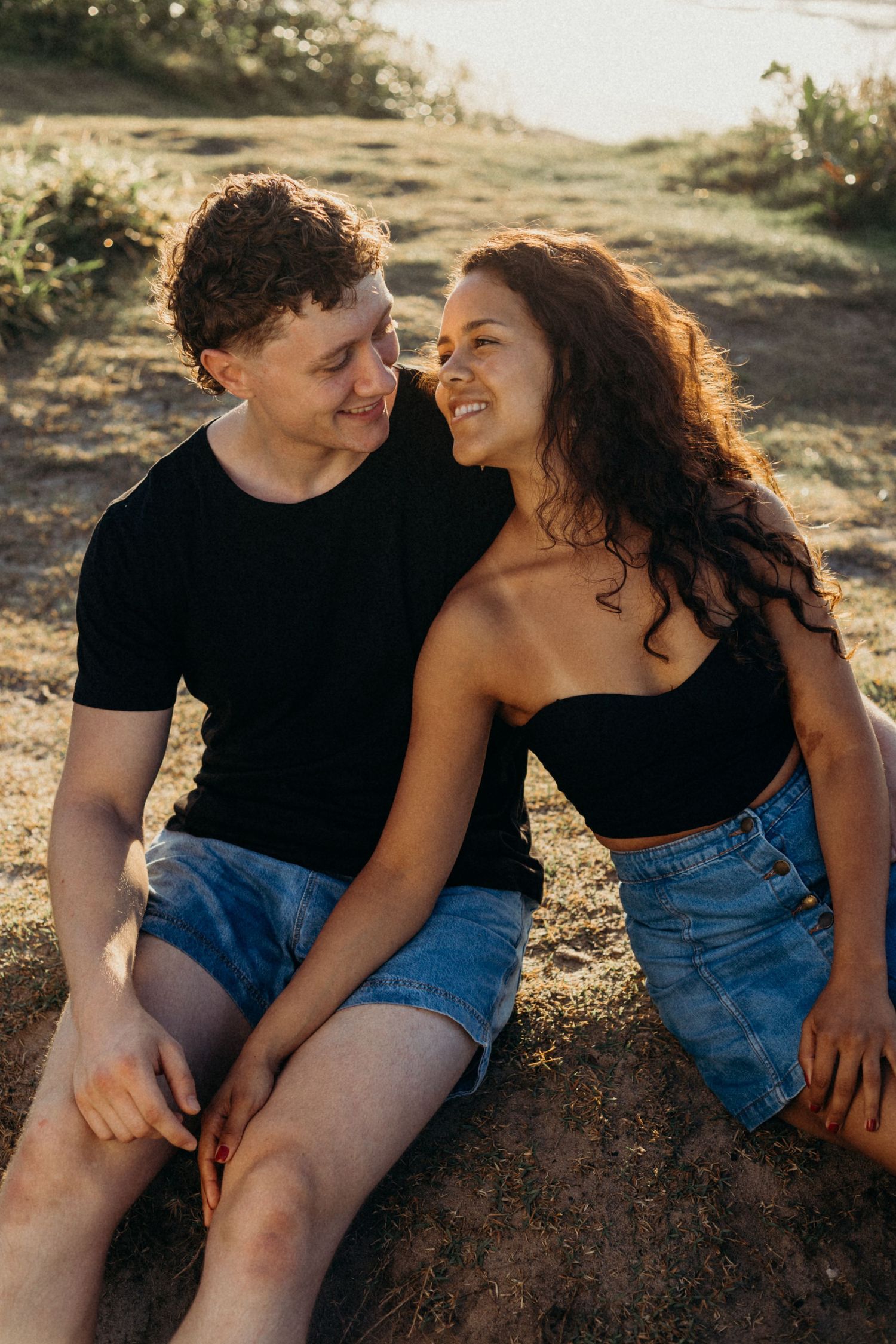 Couple sharing a laughing moment while sitting together on a hillside.