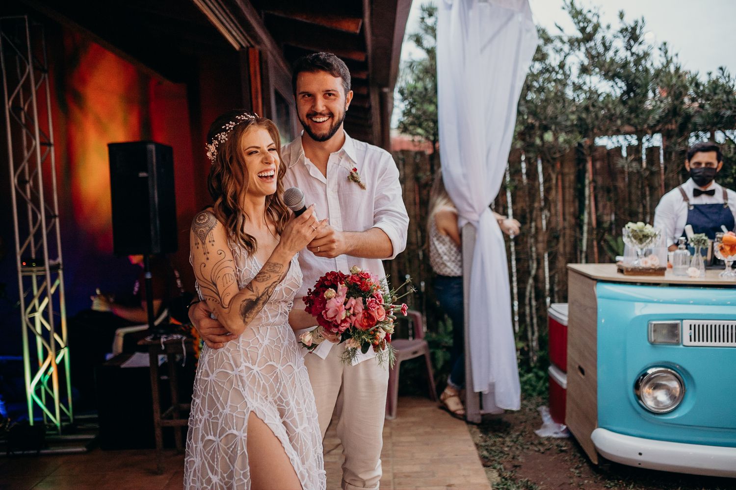 Wedding celebration near a vintage blue van with romantic decorations and lighting.