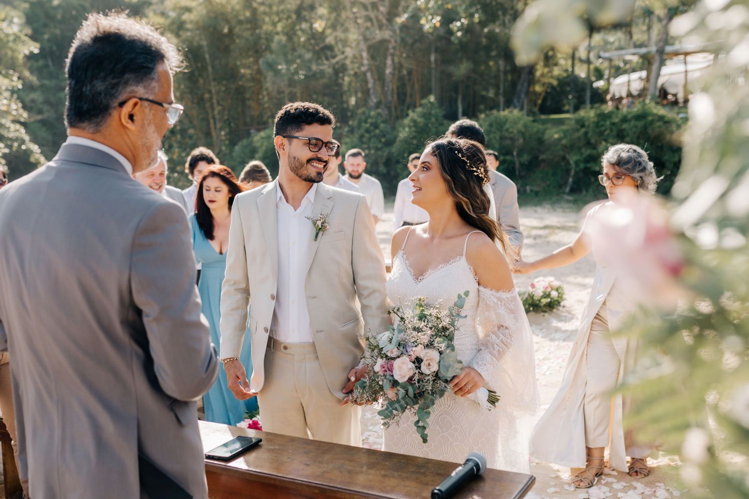 Wedding ceremony participants lined up along beach path during sunny celebration.