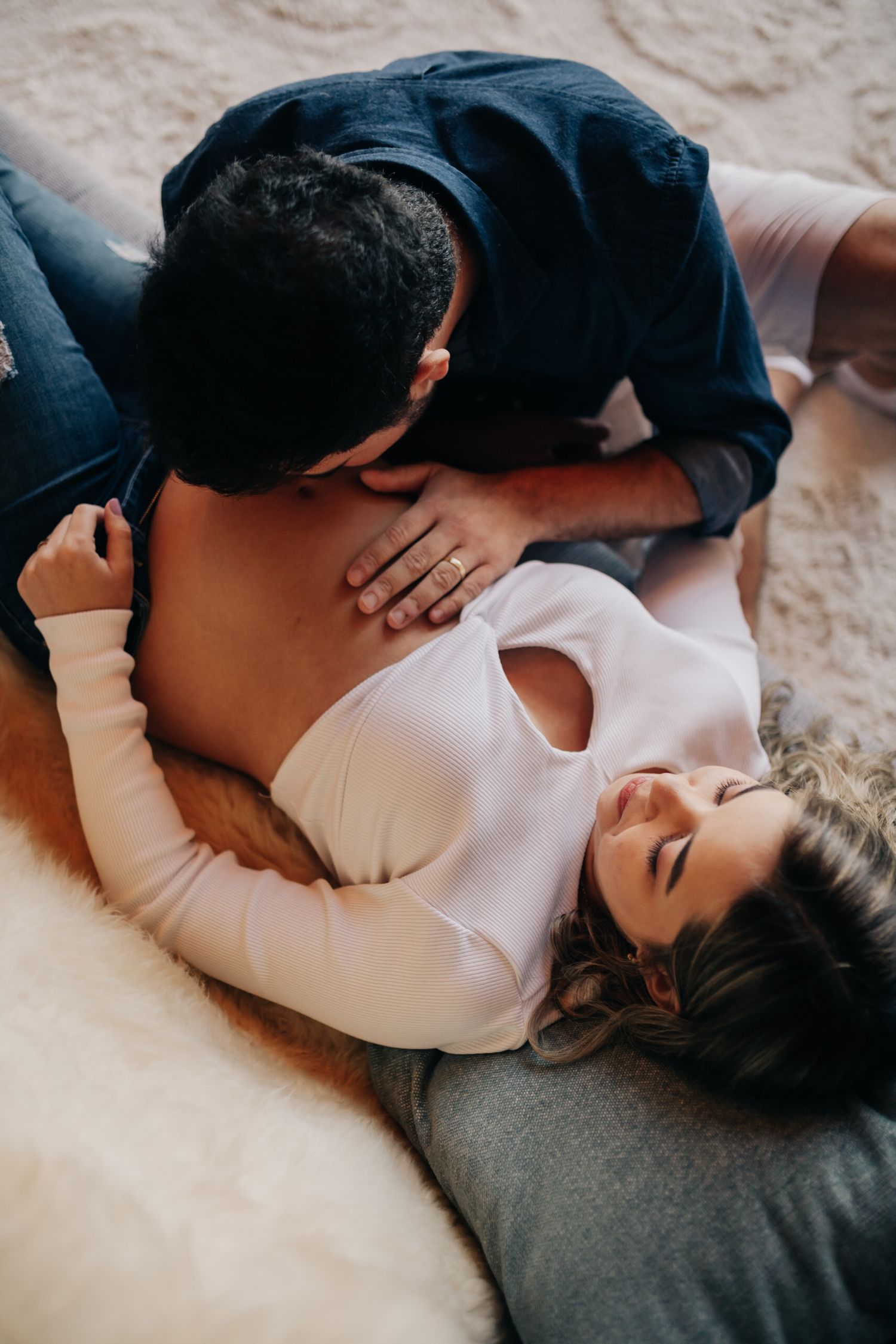 Intimate couple resting together in soft lighting during a lifestyle photoshoot.