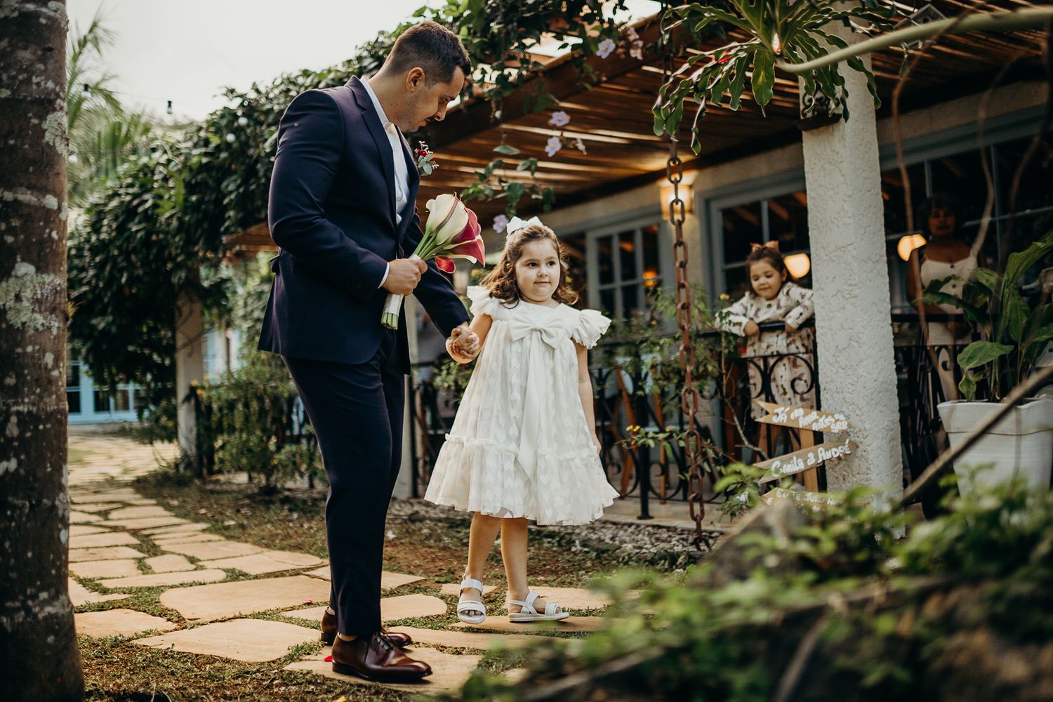 A couple shares a joyful dance moment in an outdoor garden setting during a wedding celebration.
