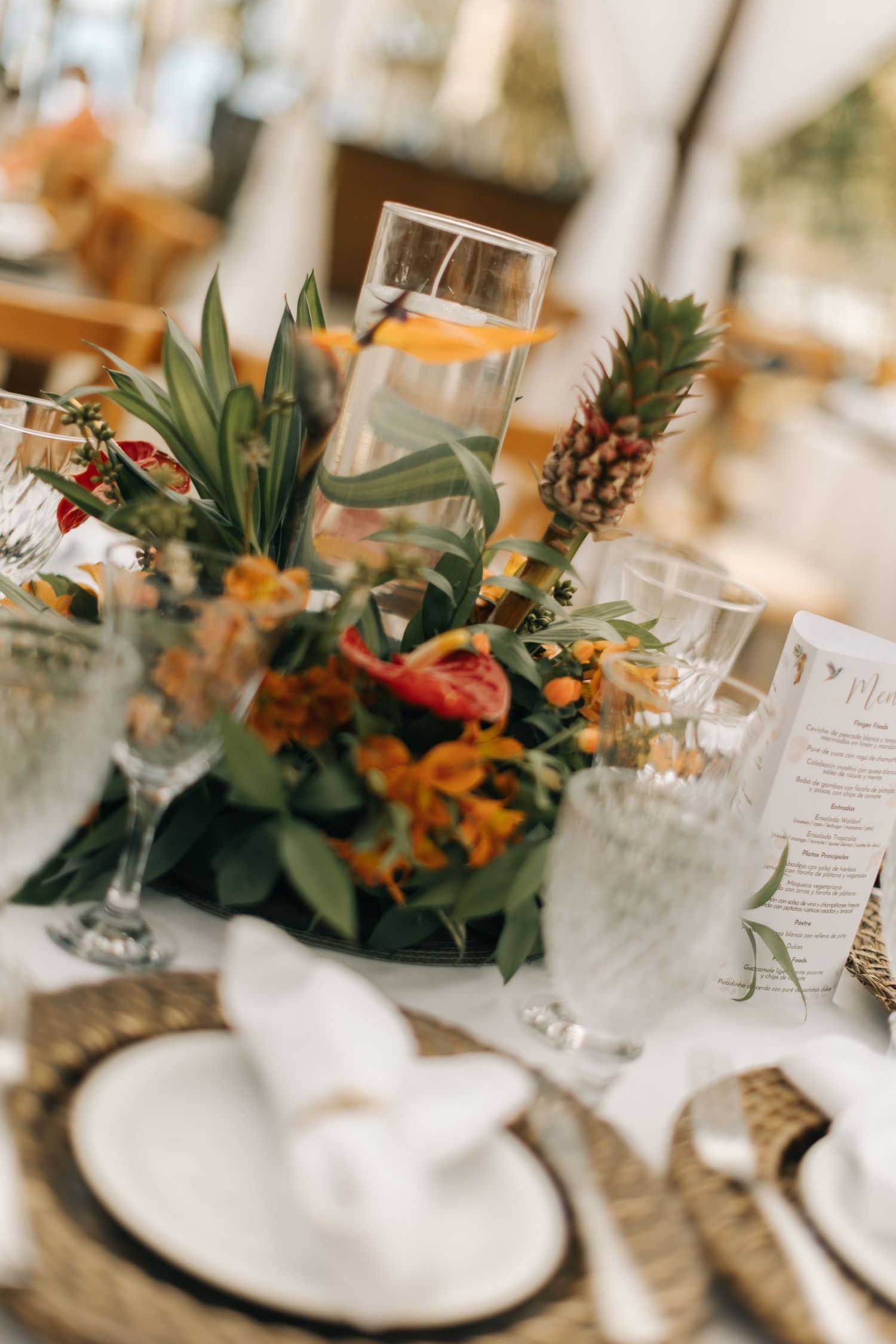 Elegant table setting with tropical floral centerpiece and glassware at wedding reception.