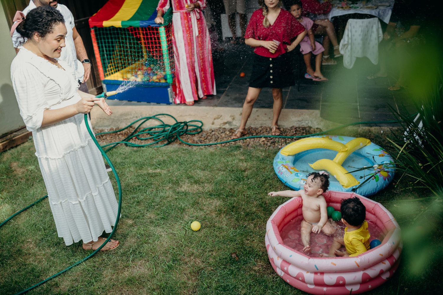 Outdoor party setup with colorful decorations and inflatable pools in a backyard setting.
