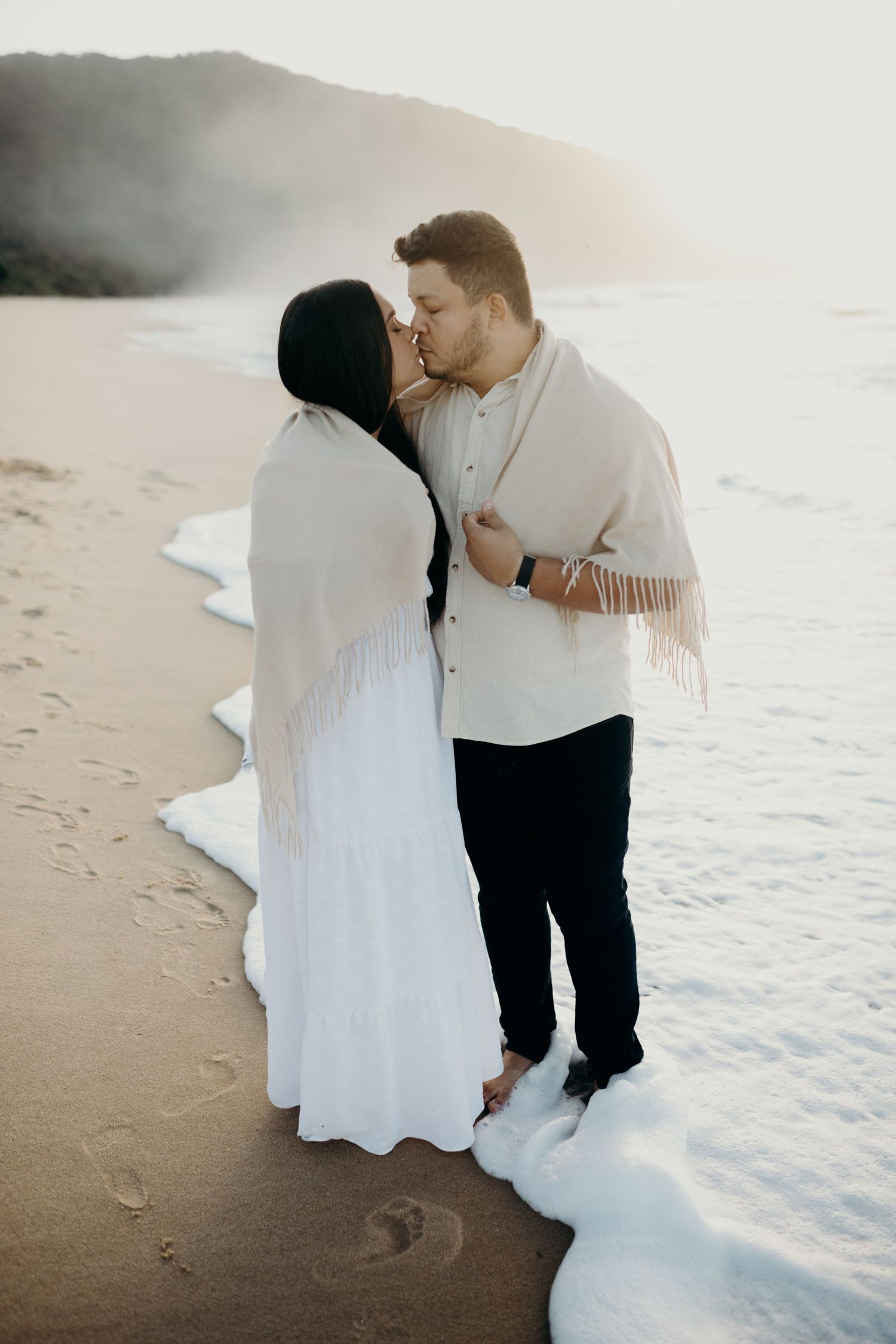 Couple shares intimate moments on a serene beach during sunset.