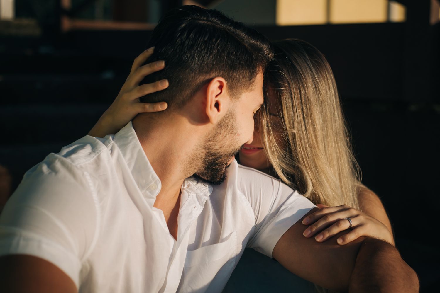 Romantic silhouette of couple sharing an intimate moment in dramatic lighting.