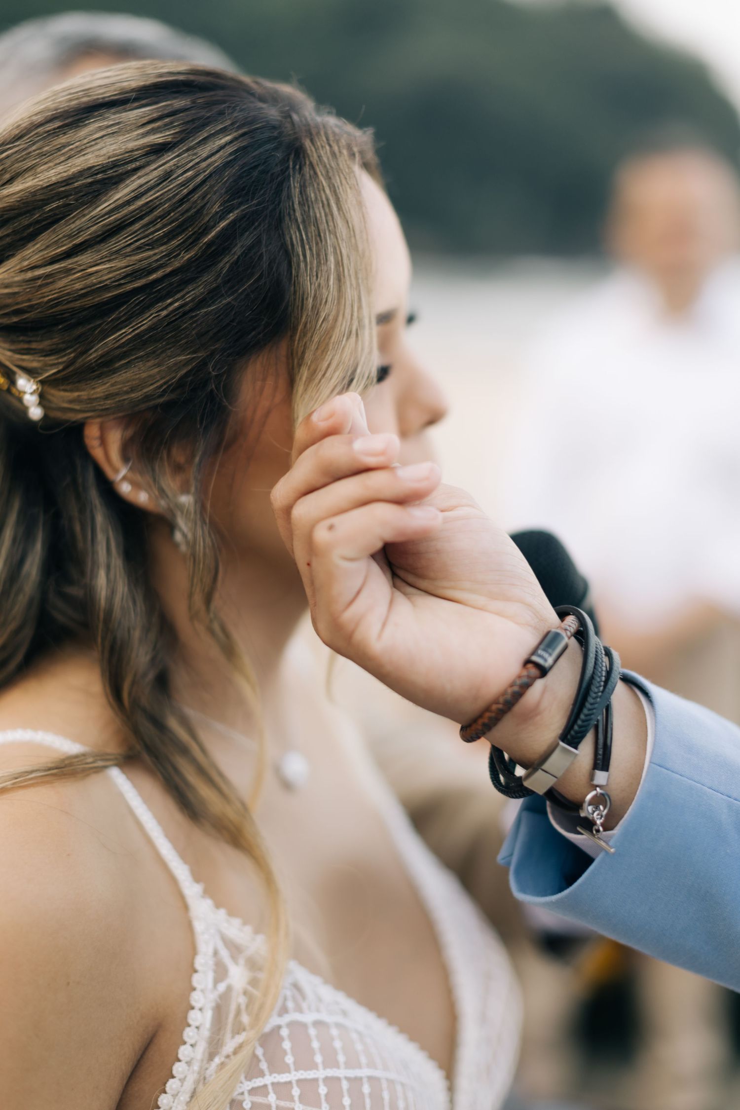 Emotional moment captured during beach wedding ceremony with tender gesture.