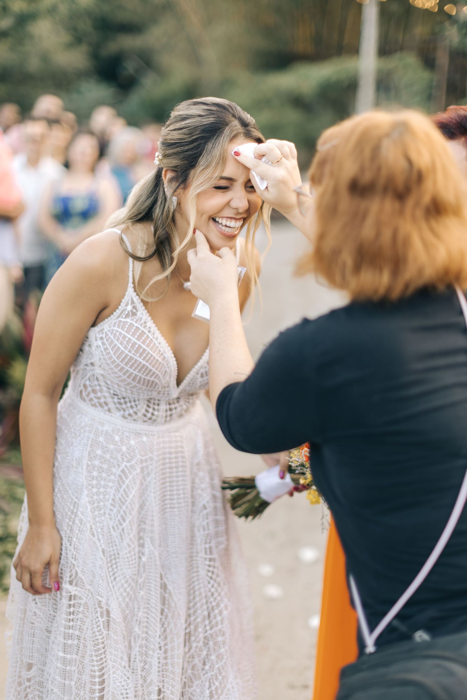 Candid laughter during wedding celebration with lace dress and string lights overhead.