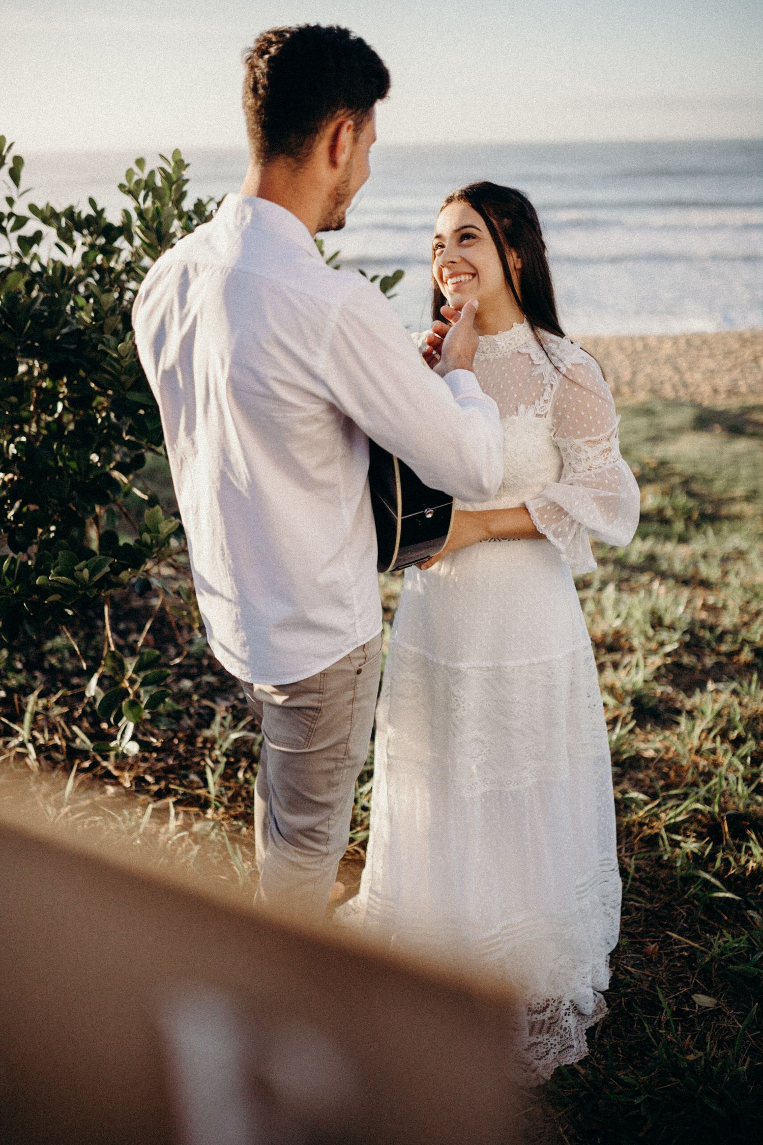 Joyful couple laughs together during seaside photo session.