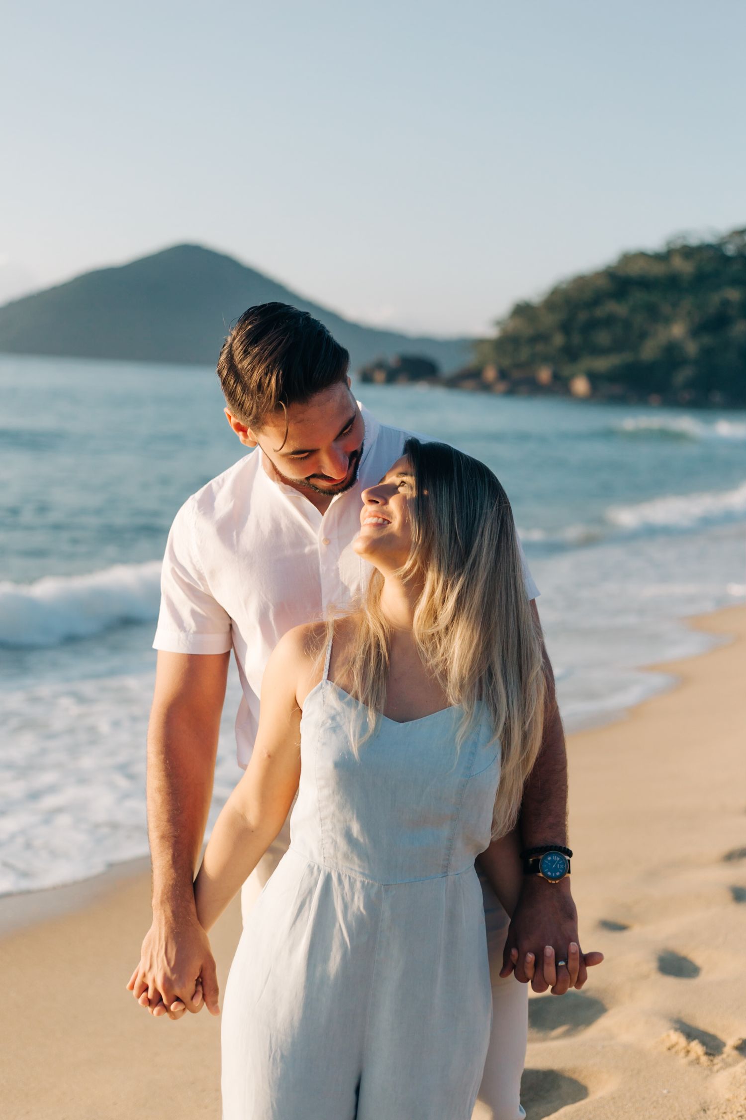 Tender moment between couple in white clothing on a beautiful coastal beach at sunset.
