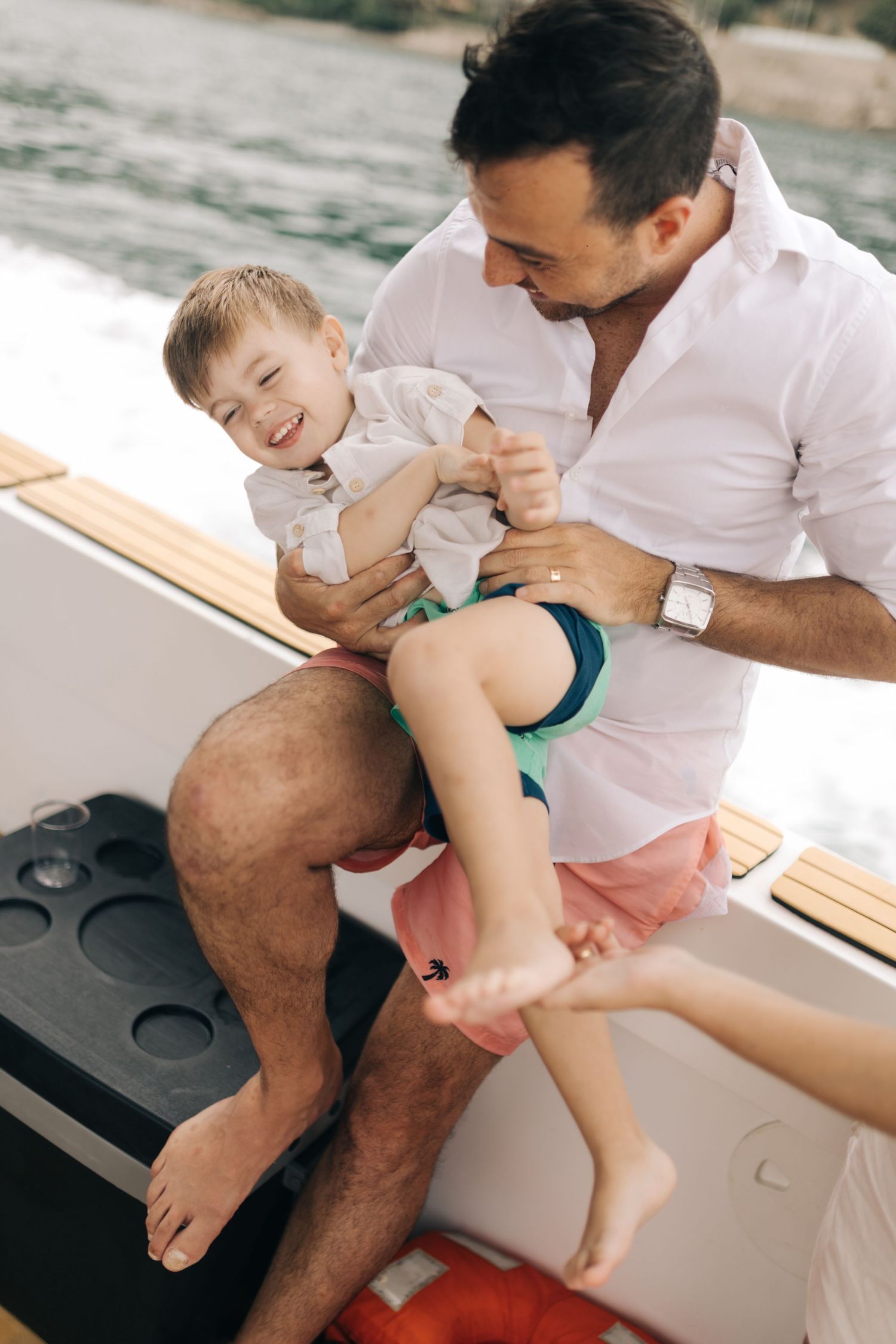 A playful moment shared between parent and child laughing together on a boat.