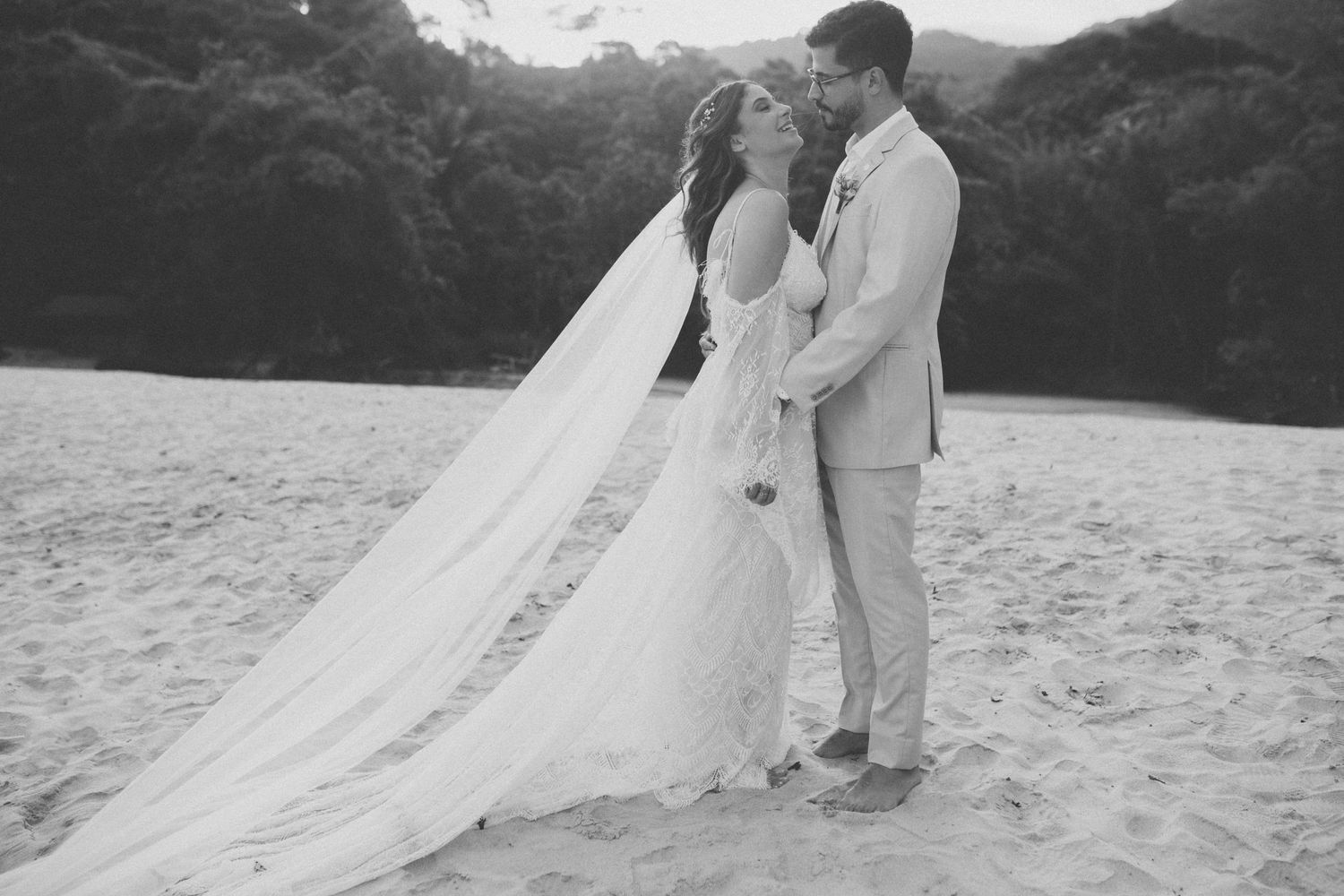 Black and white beach wedding photo showing couple in romantic embrace.