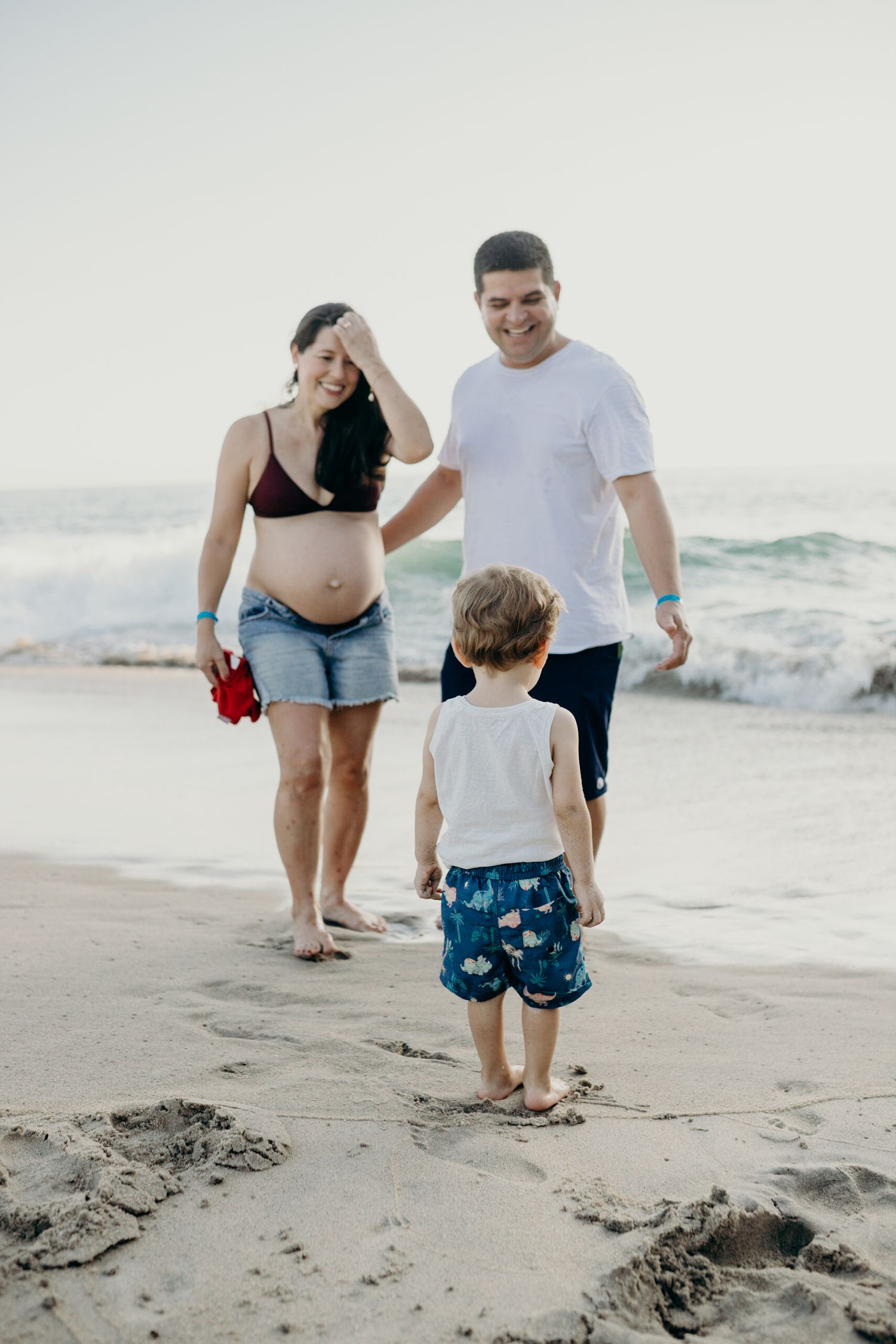 Beachgoers enjoying family time near the ocean waves on a sandy shore.