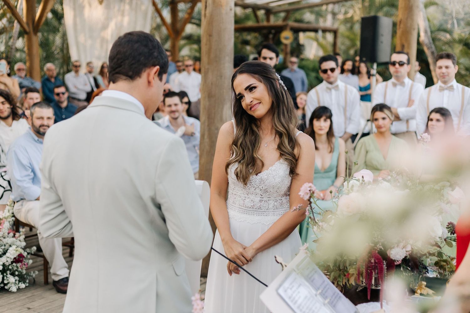 A tender moment during a wedding ceremony with guests seated in an outdoor garden setting.