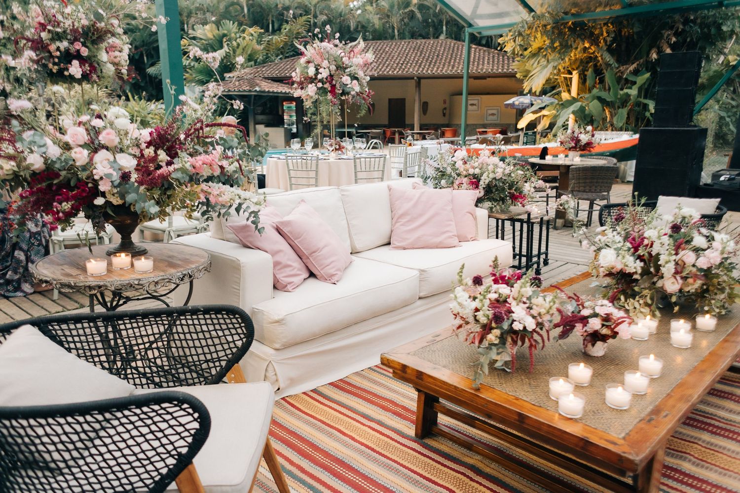 An elegant lounge area with white sofa and pink floral arrangements at a wedding reception.