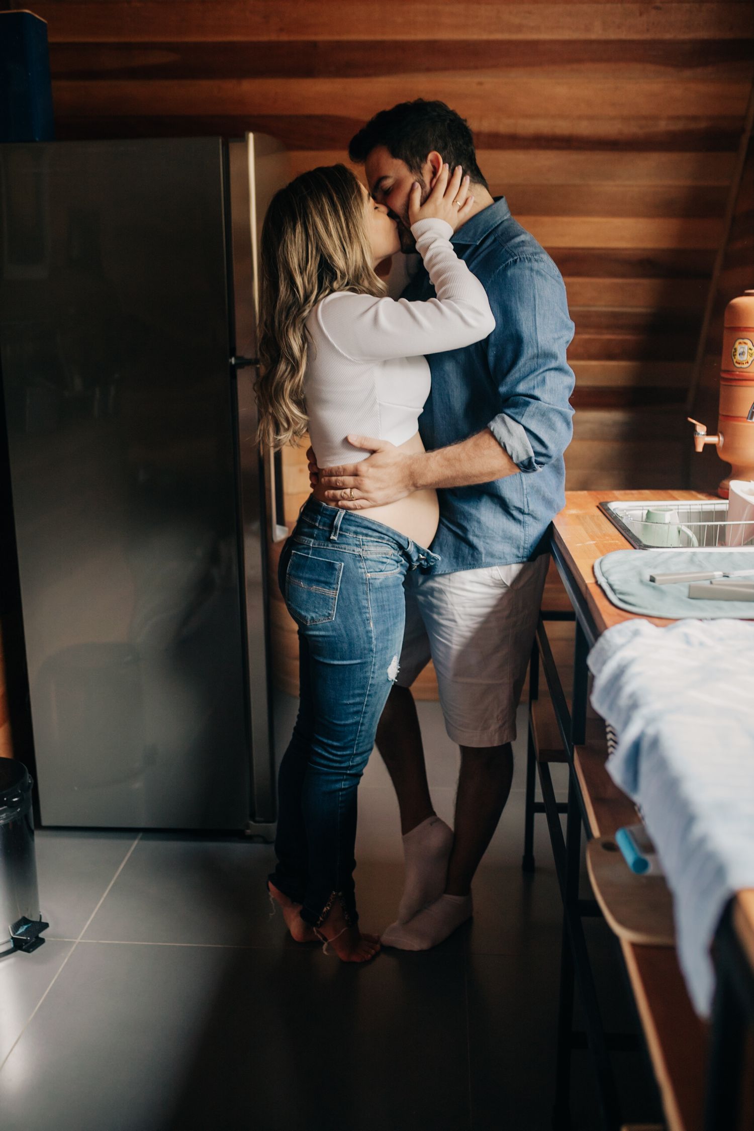 Couple sharing intimate moments against wooden walls in a rustic interior.