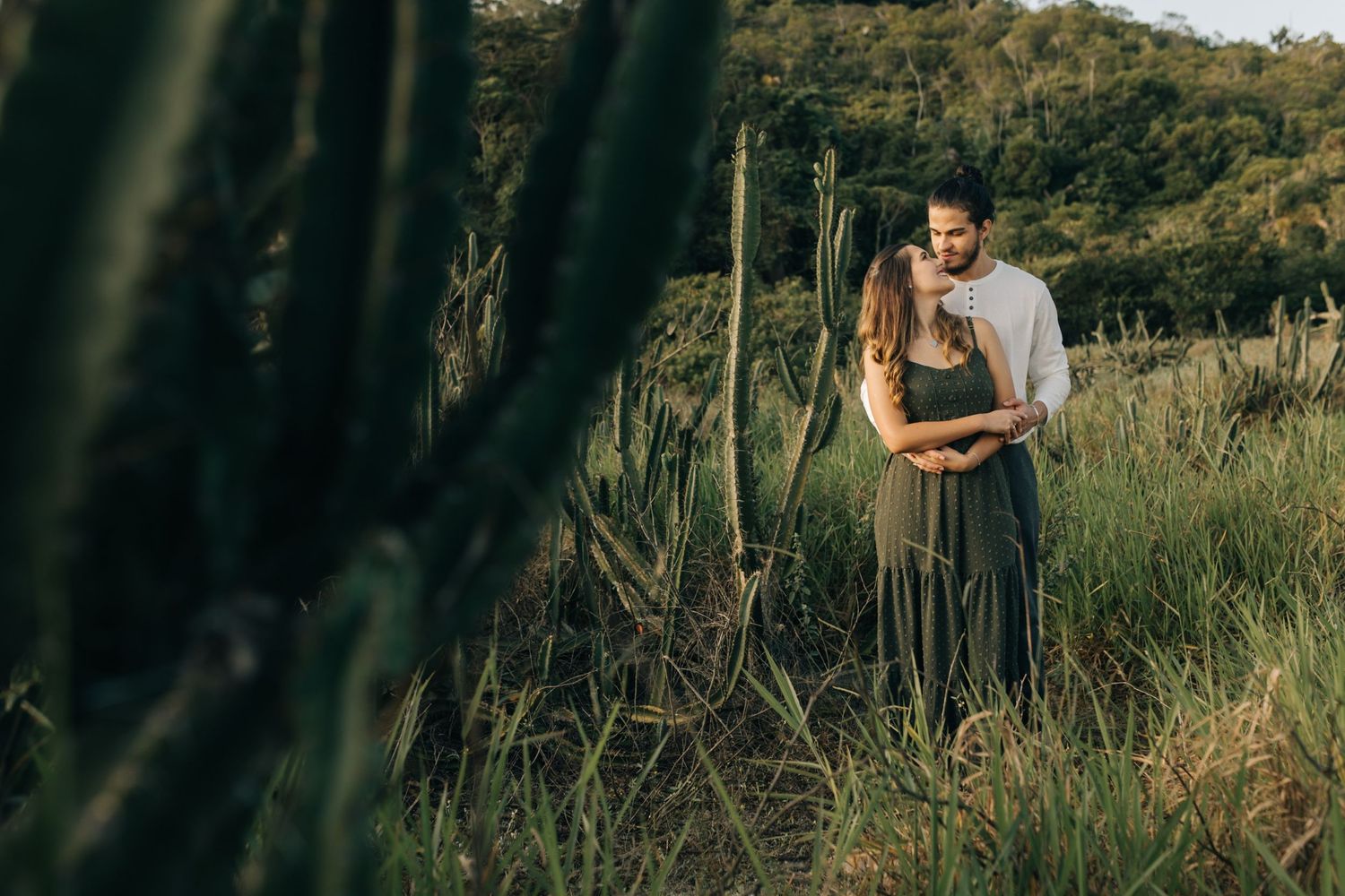 Couple strolling through wild grass field against a scenic mountain backdrop.