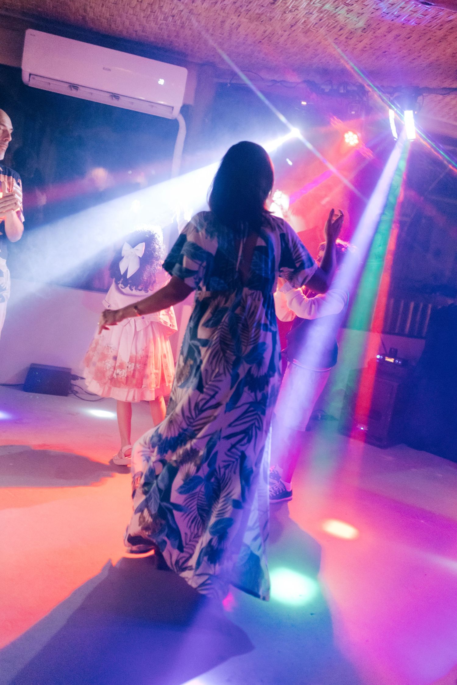 Colorful disco lights illuminate a dance floor at a wedding reception.