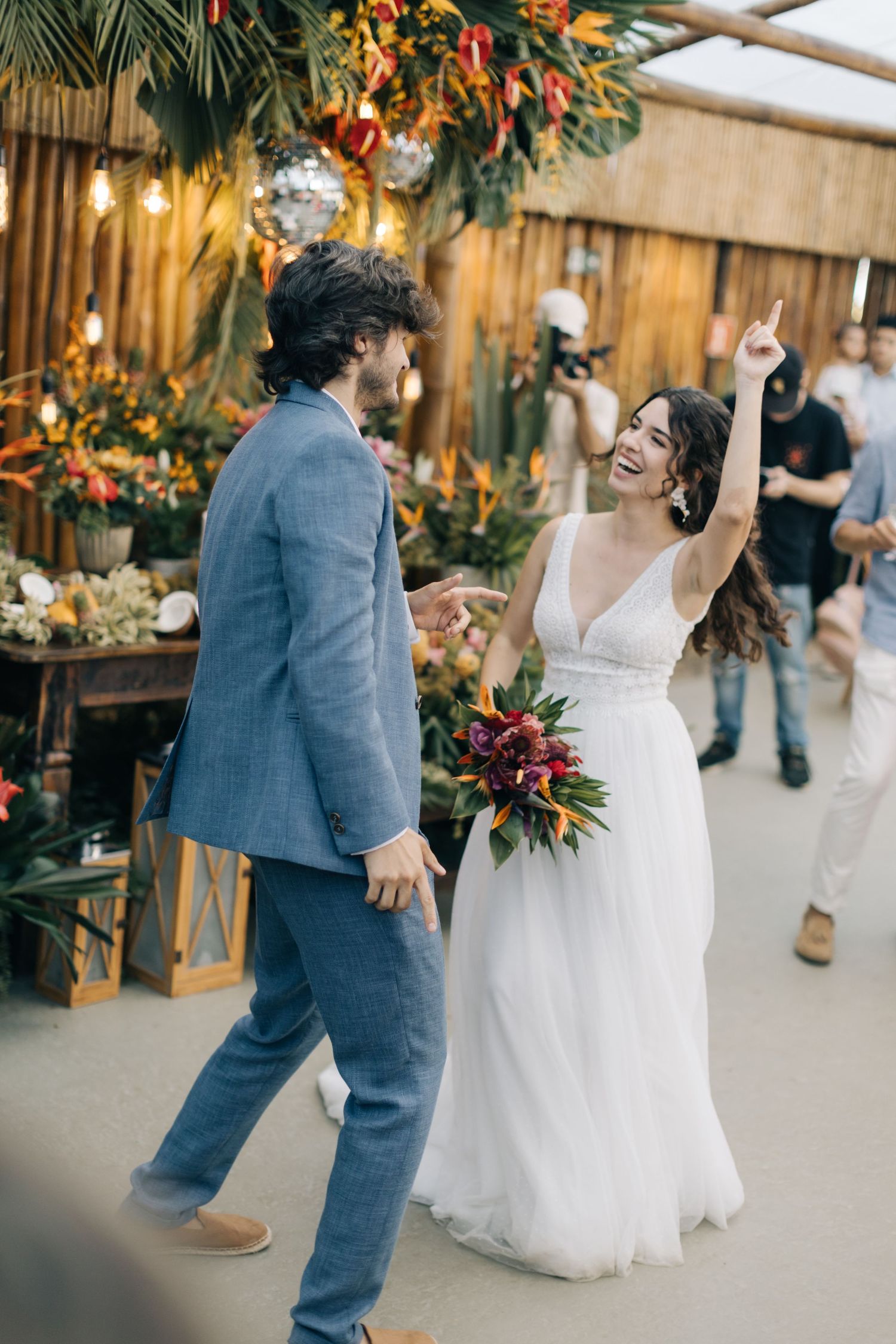 Celebration moment at a wedding reception with tropical decor and string lights.