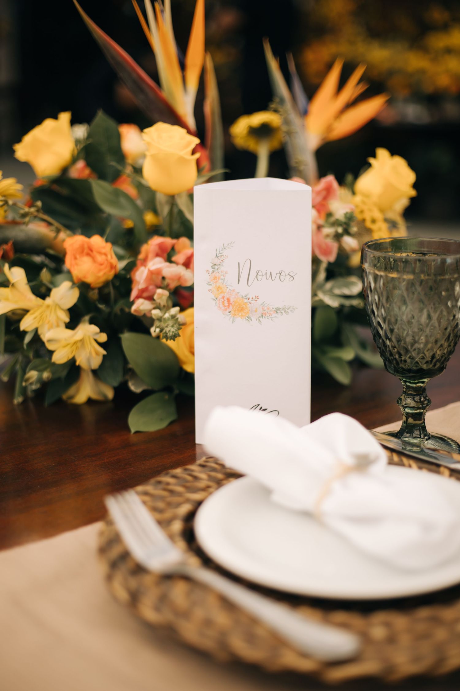 Elegant table setting with yellow daffodils, white napkins, and place cards on a rustic wooden surface.