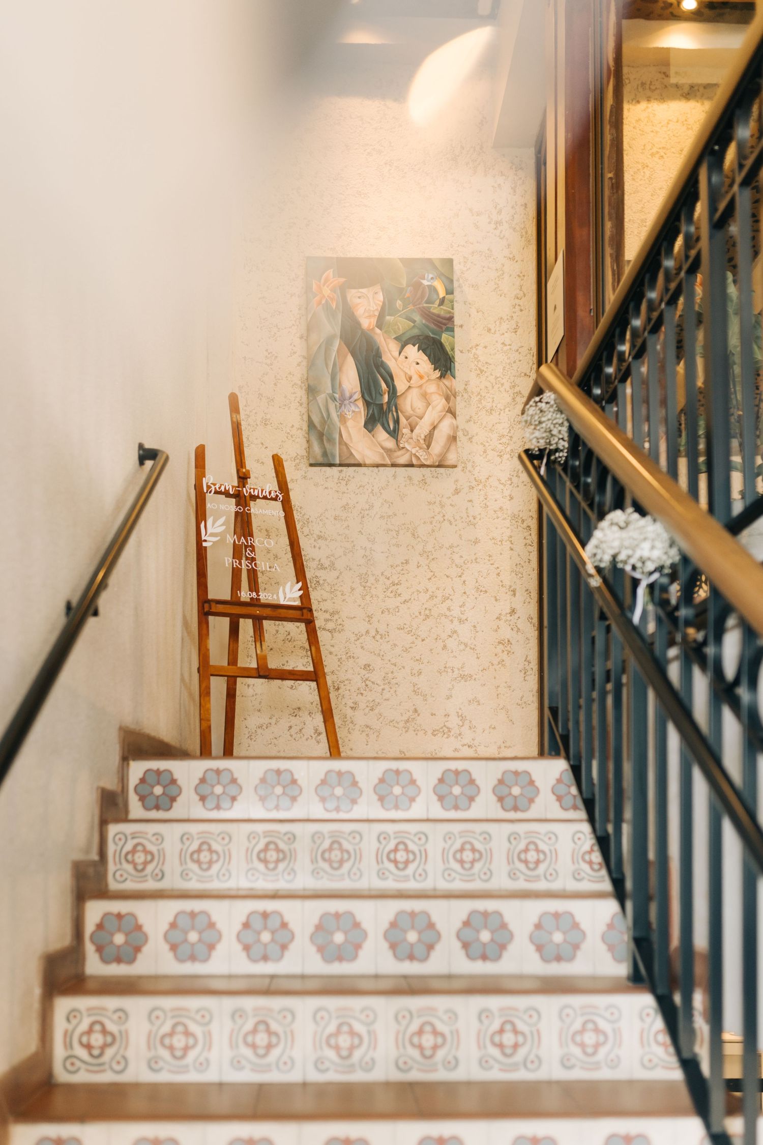 Decorative tiled staircase with wooden handrail and easel.