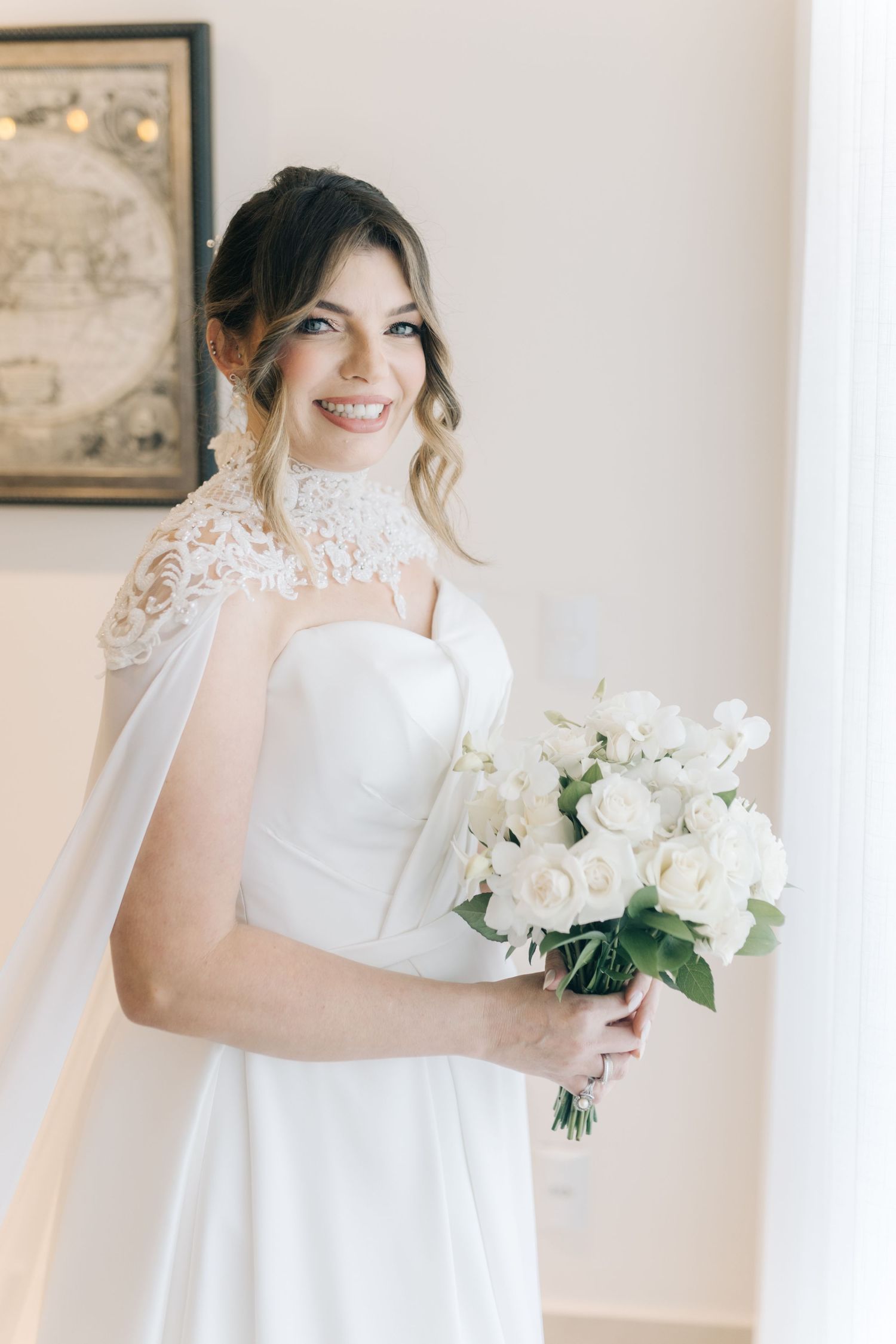 A close-up shot of a bride wearing a delicate lace gown while holding a white floral bouquet.