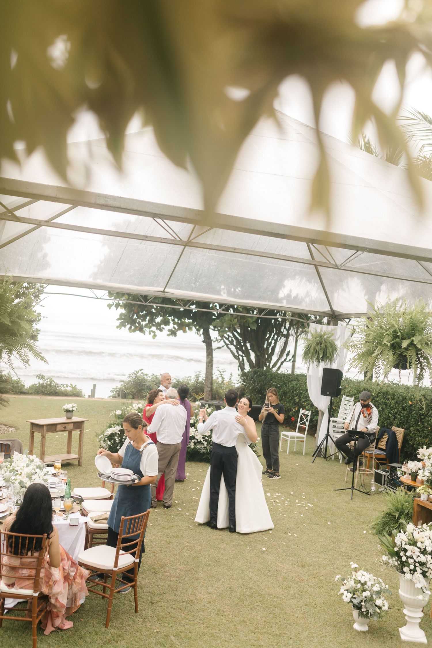 Wedding reception under an elegant tent with guests mingling and dancing.